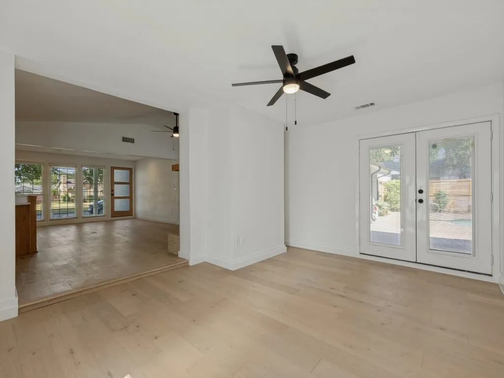 Light wood-finish flooring, white walls, and a modern ceiling fan