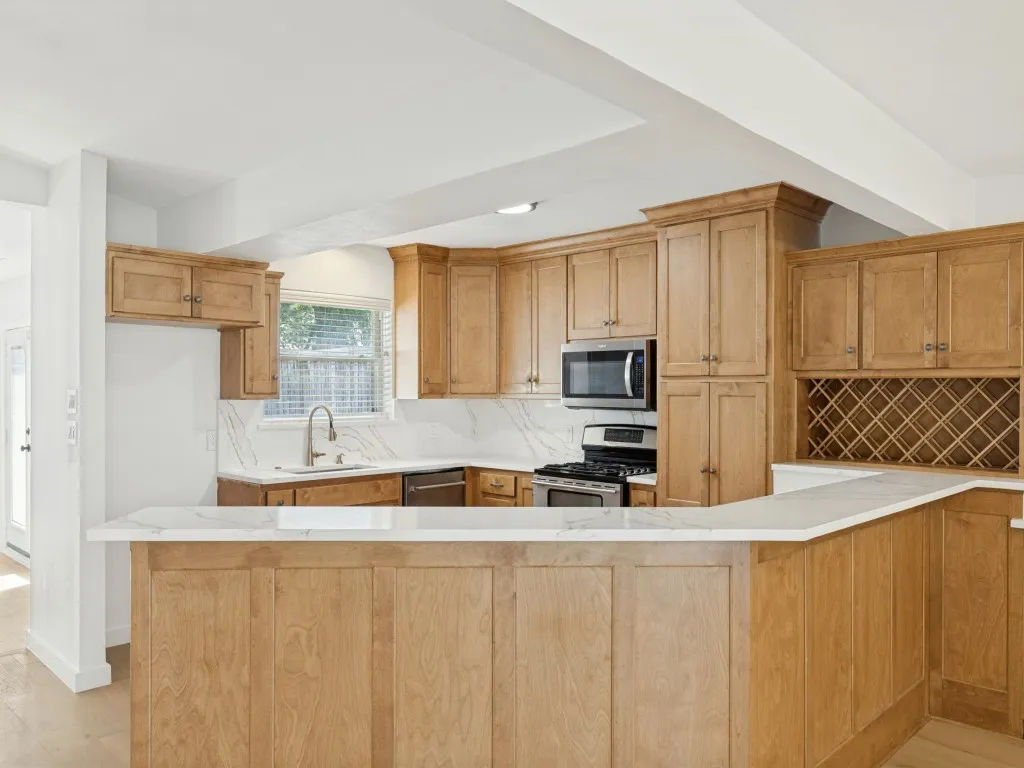 Kitchen featuring extensive wood cabinetry, stainless steel appliances, white countertops, and a built-in wine rack