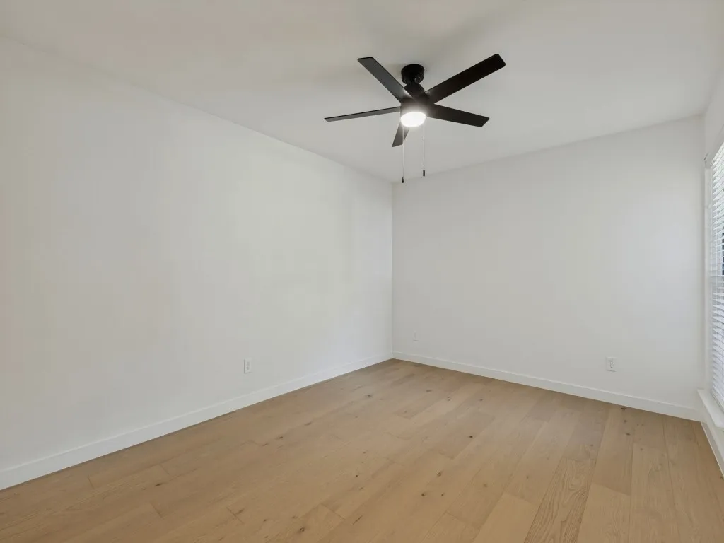Wood-finish flooring, white walls, and a contemporary ceiling fan with integrated lighting