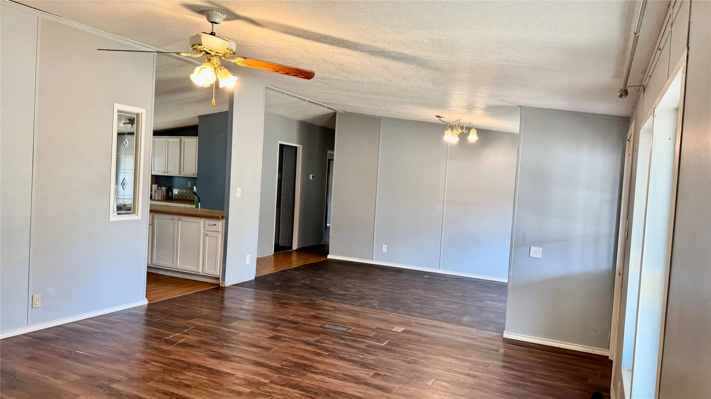 Wood-finish flooring throughout the main living area, featuring a ceiling fan with integrated lighting and recessed lighting fixtures