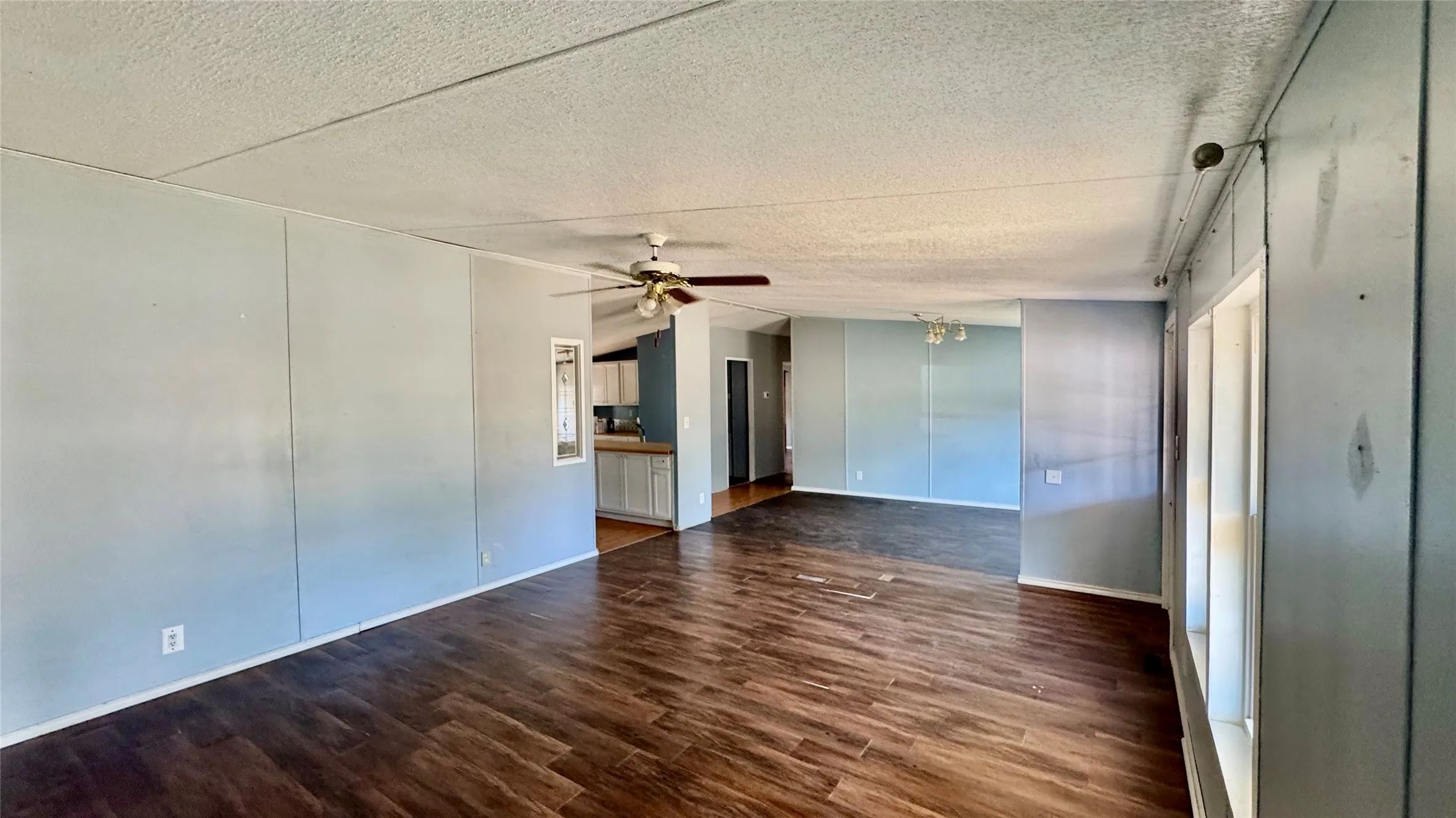 Wood-finish flooring throughout, light gray panel walls, and a ceiling fan with integrated lighting