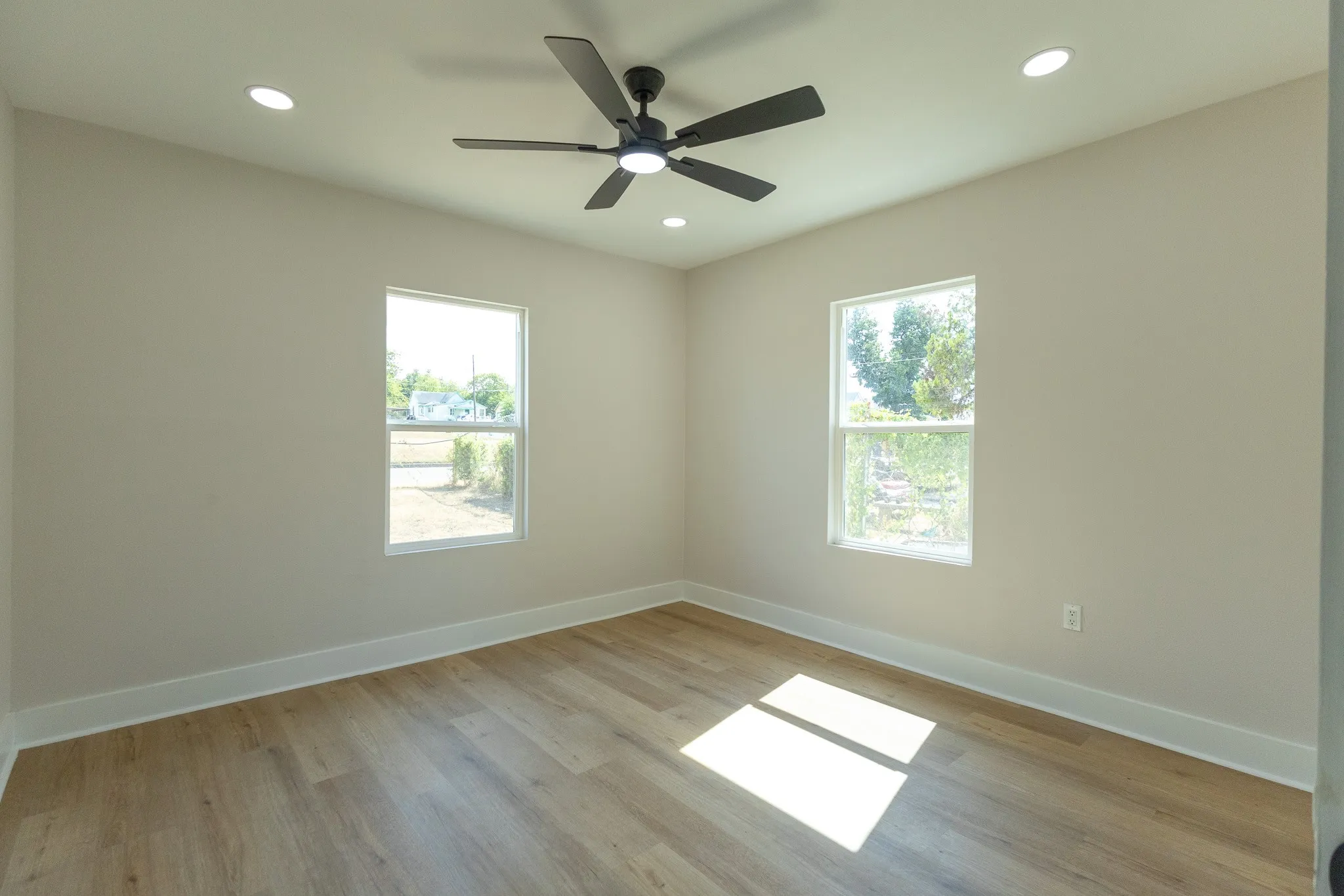 Recessed ceiling lighting, a ceiling fan with light, wood-finish flooring, and white trim