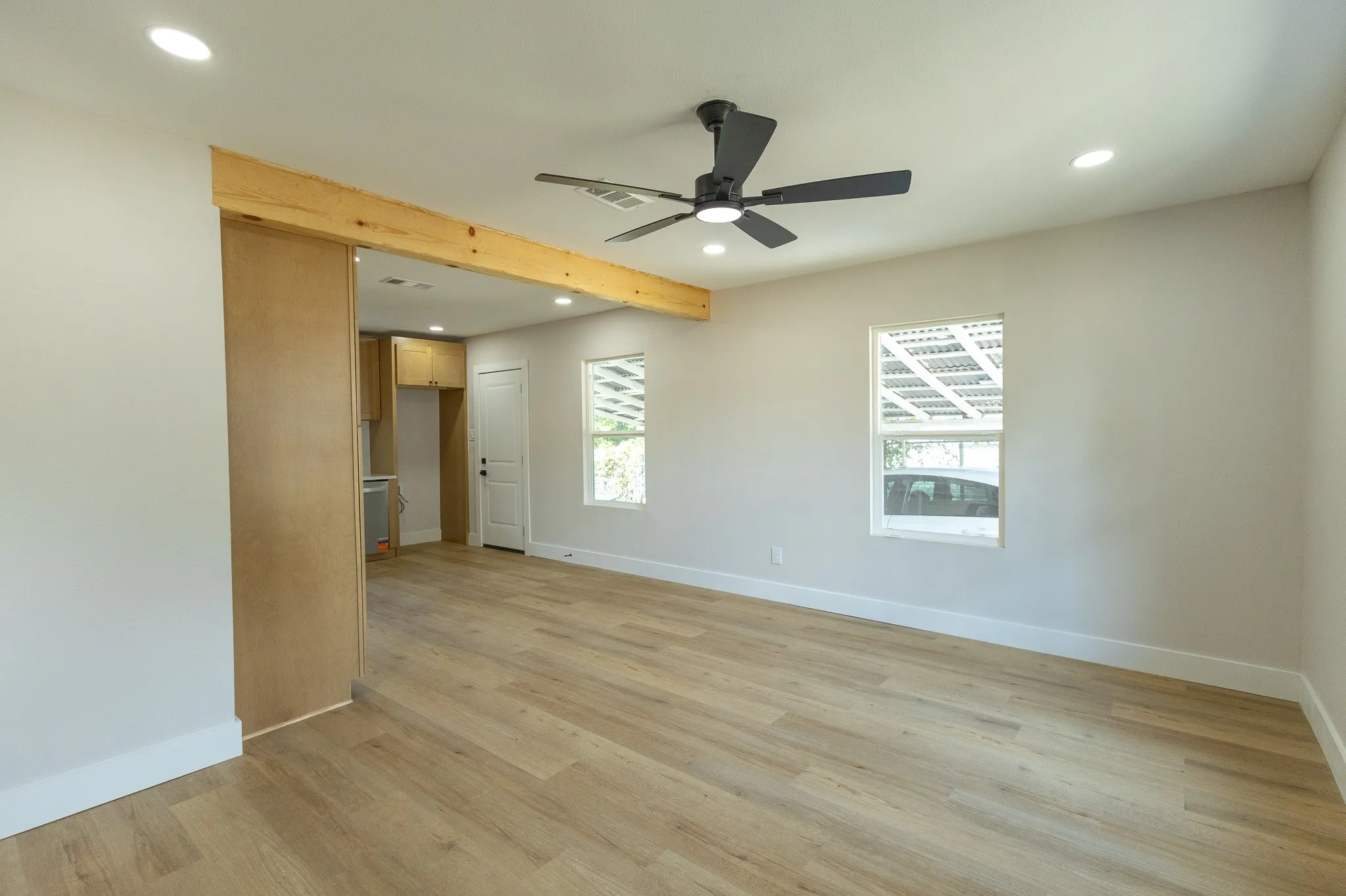 Recessed lighting, wood-finish flooring, ceiling fan, and wood beam accent