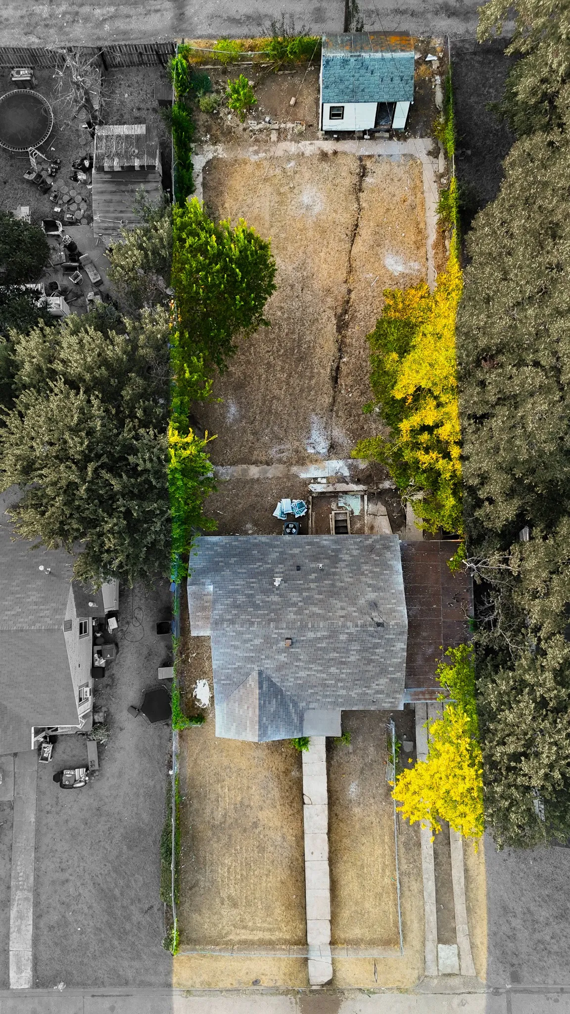 Single-story residence with a gray shingle roof, a detached shed with a blue roof, and a front walkway leading to the entrance