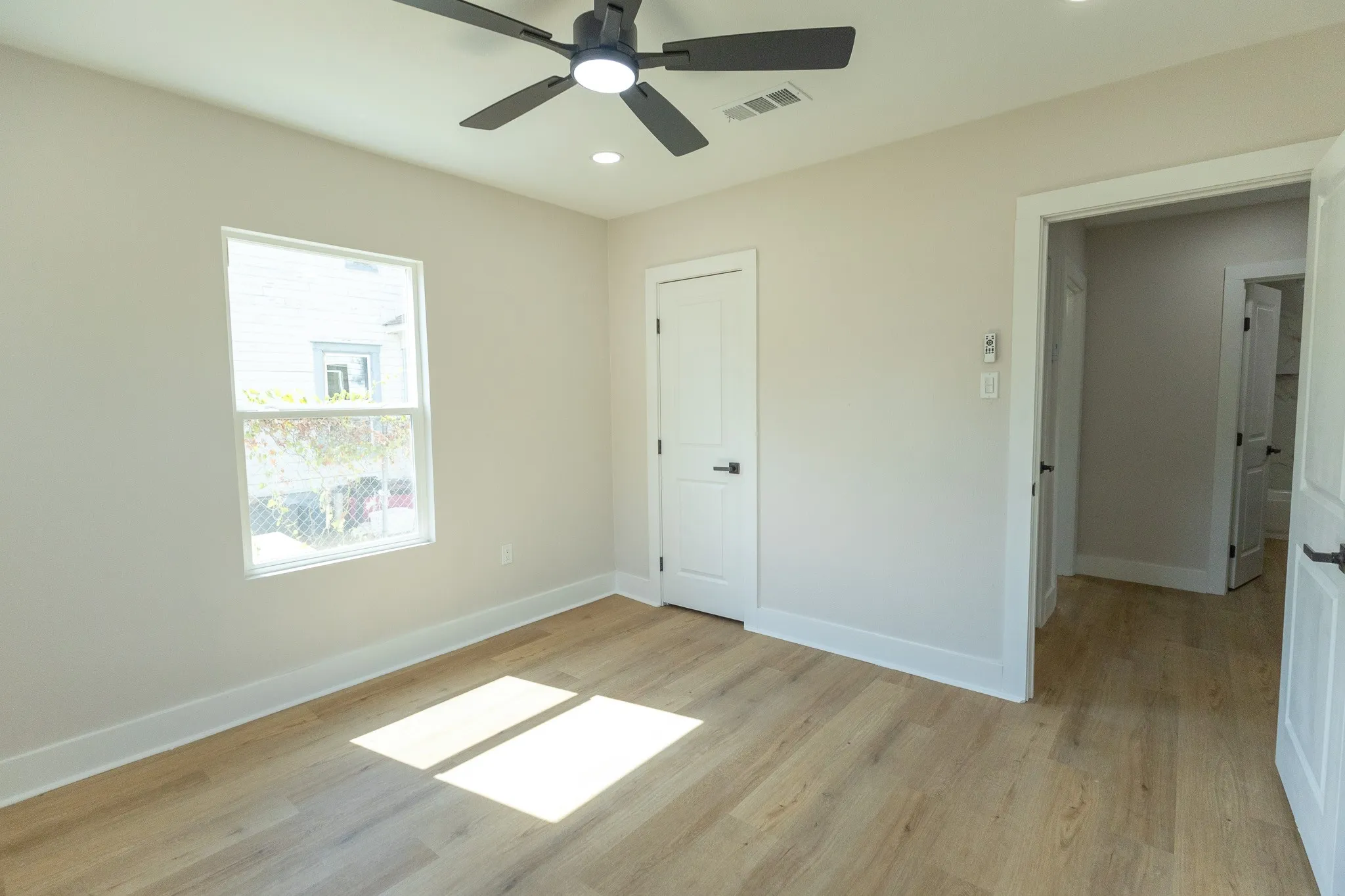 Light-toned wood-finish flooring, white trim, and a ceiling fan with integrated lighting