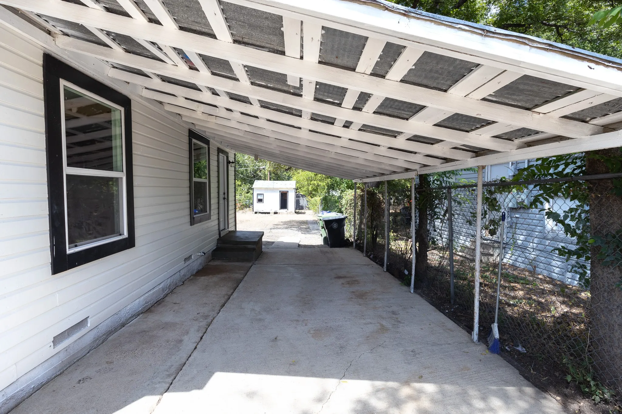 Carport with a concrete surface, white siding, and black-trimmed windows