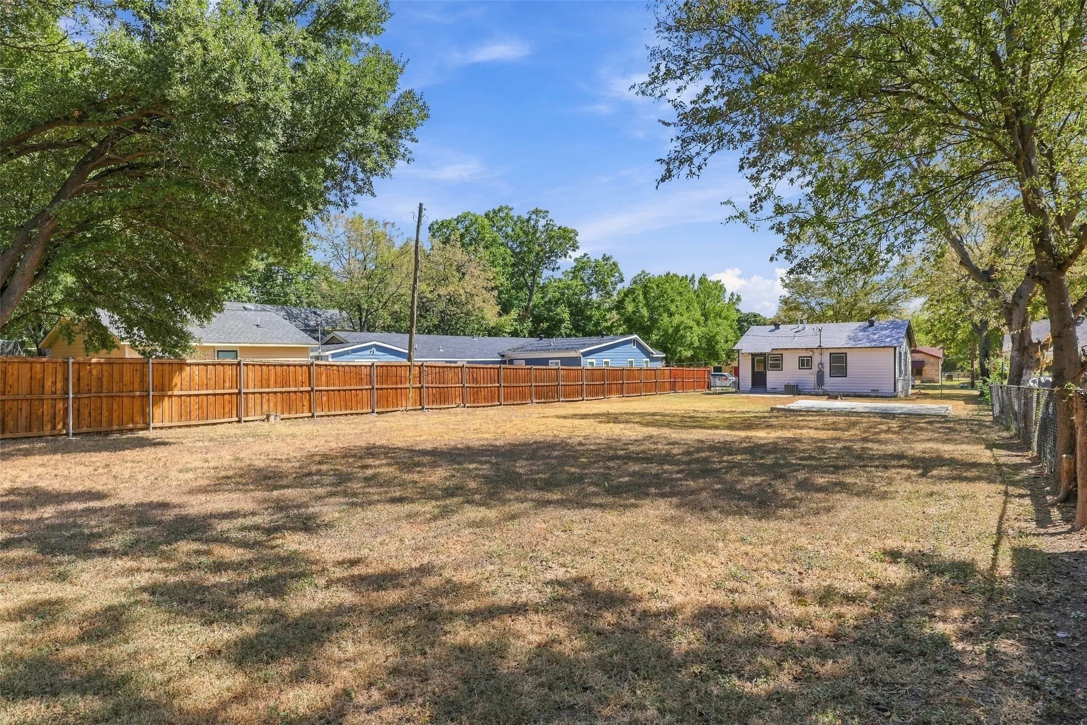 Expansive backyard with a fence and mature trees