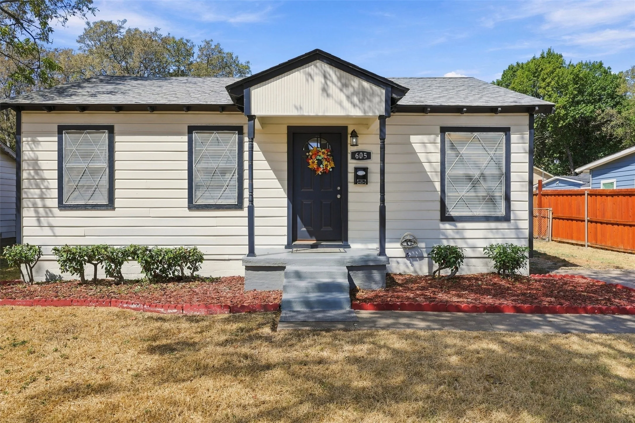 Single-story residence featuring light-colored siding, a dark front door, and a covered porch entry