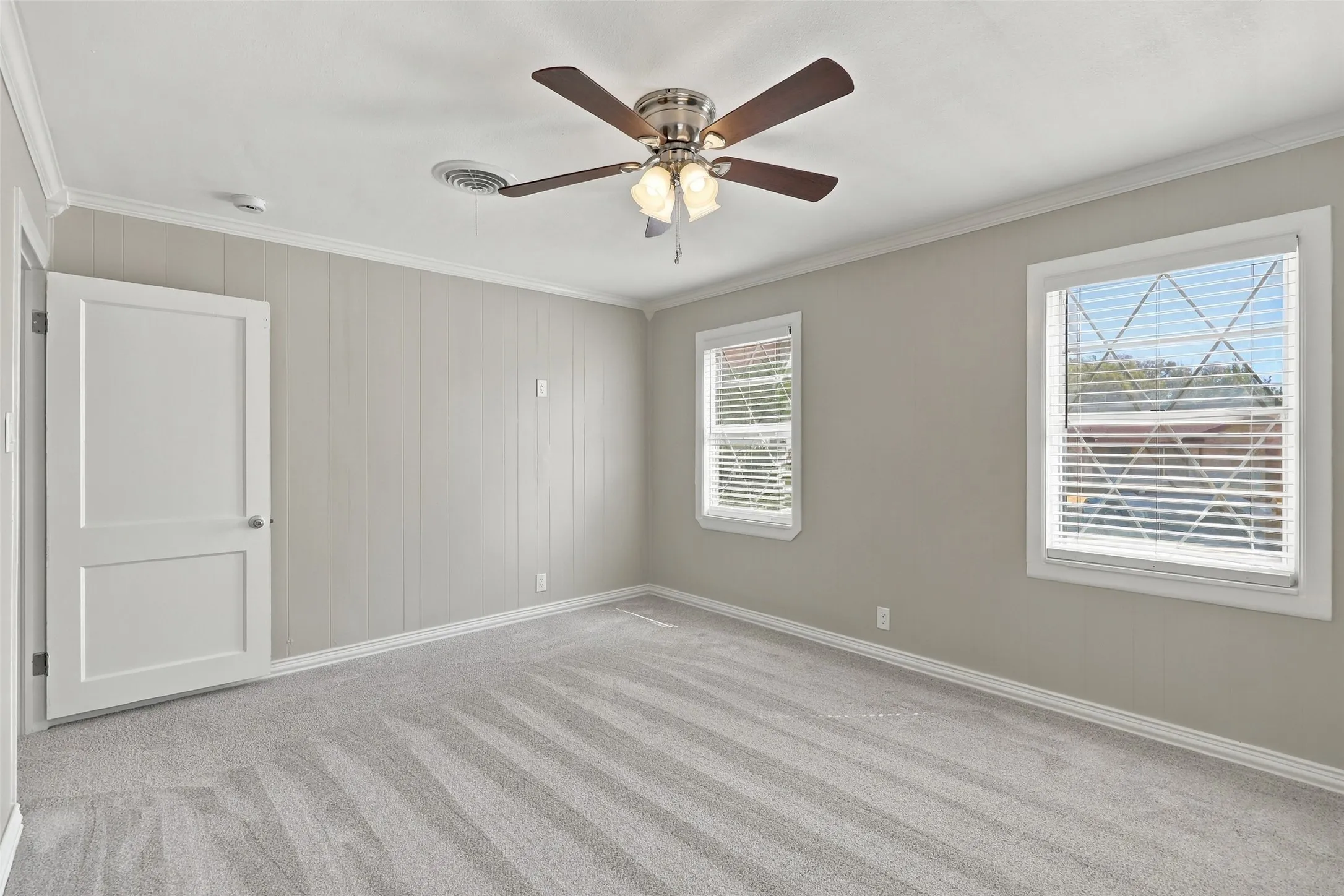Plush carpet flooring complements pale gray walls with vertical paneling