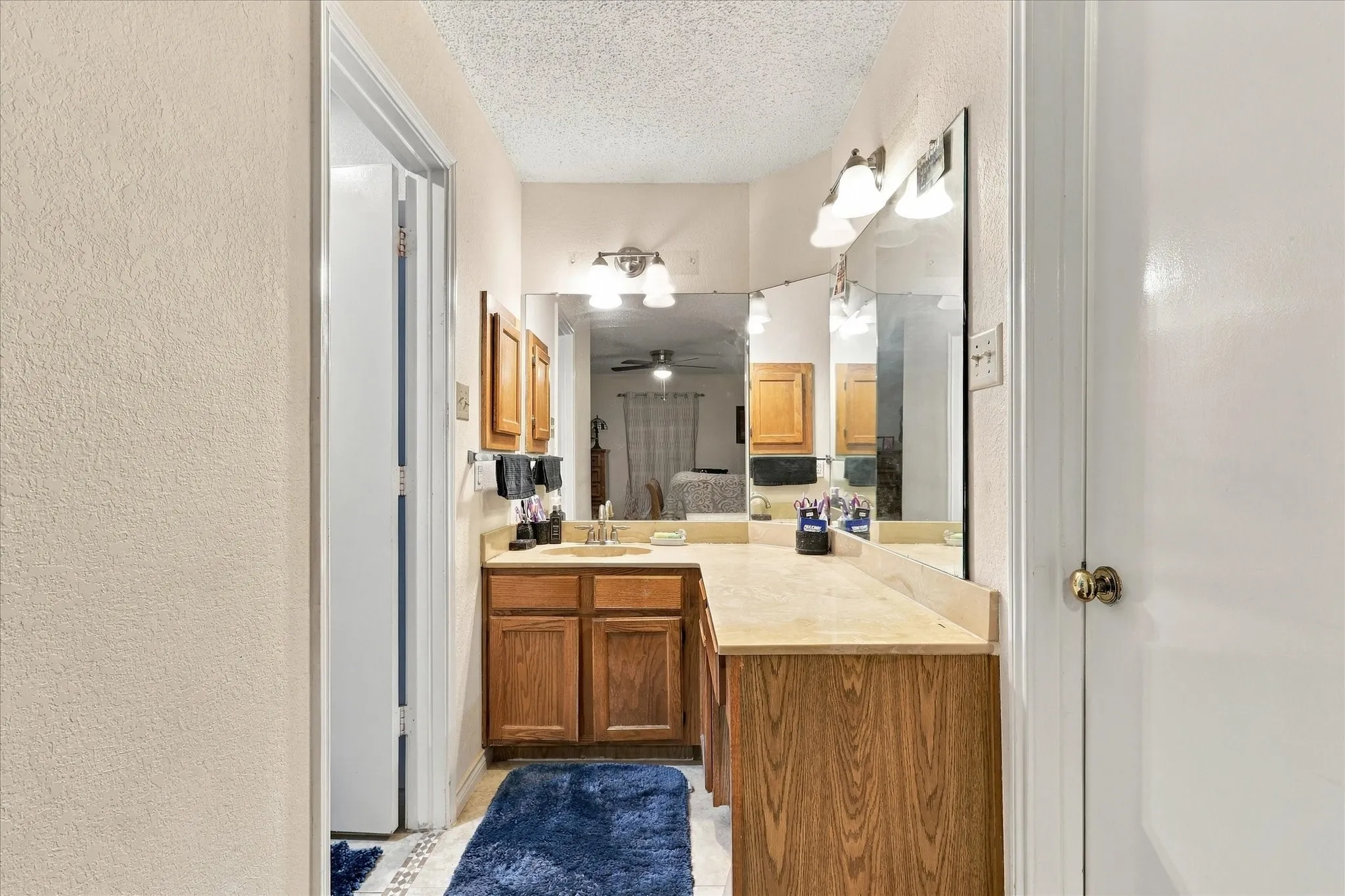 Double vanity with integrated sink, wood-finish cabinetry, and overhead lighting fixtures