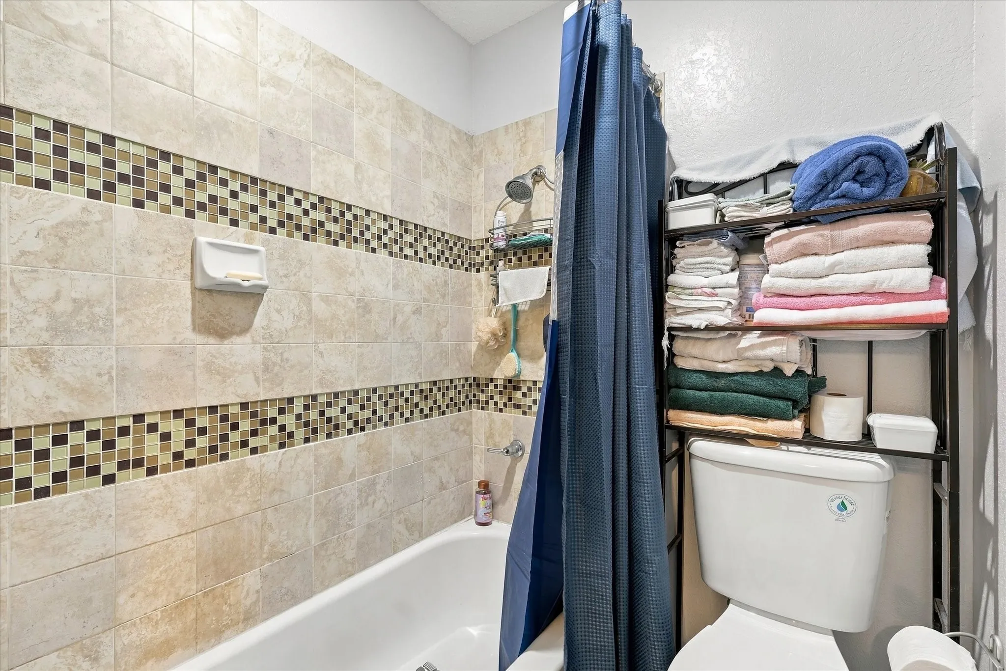 Tiled shower surround with mosaic accent bands and a built-in bathtub
