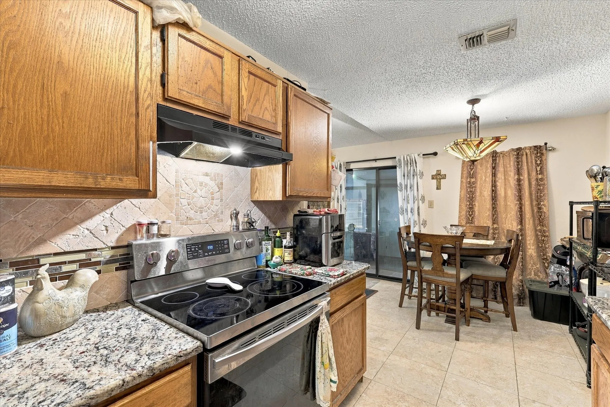 Wood cabinetry with stainless steel range and granite-style countertops