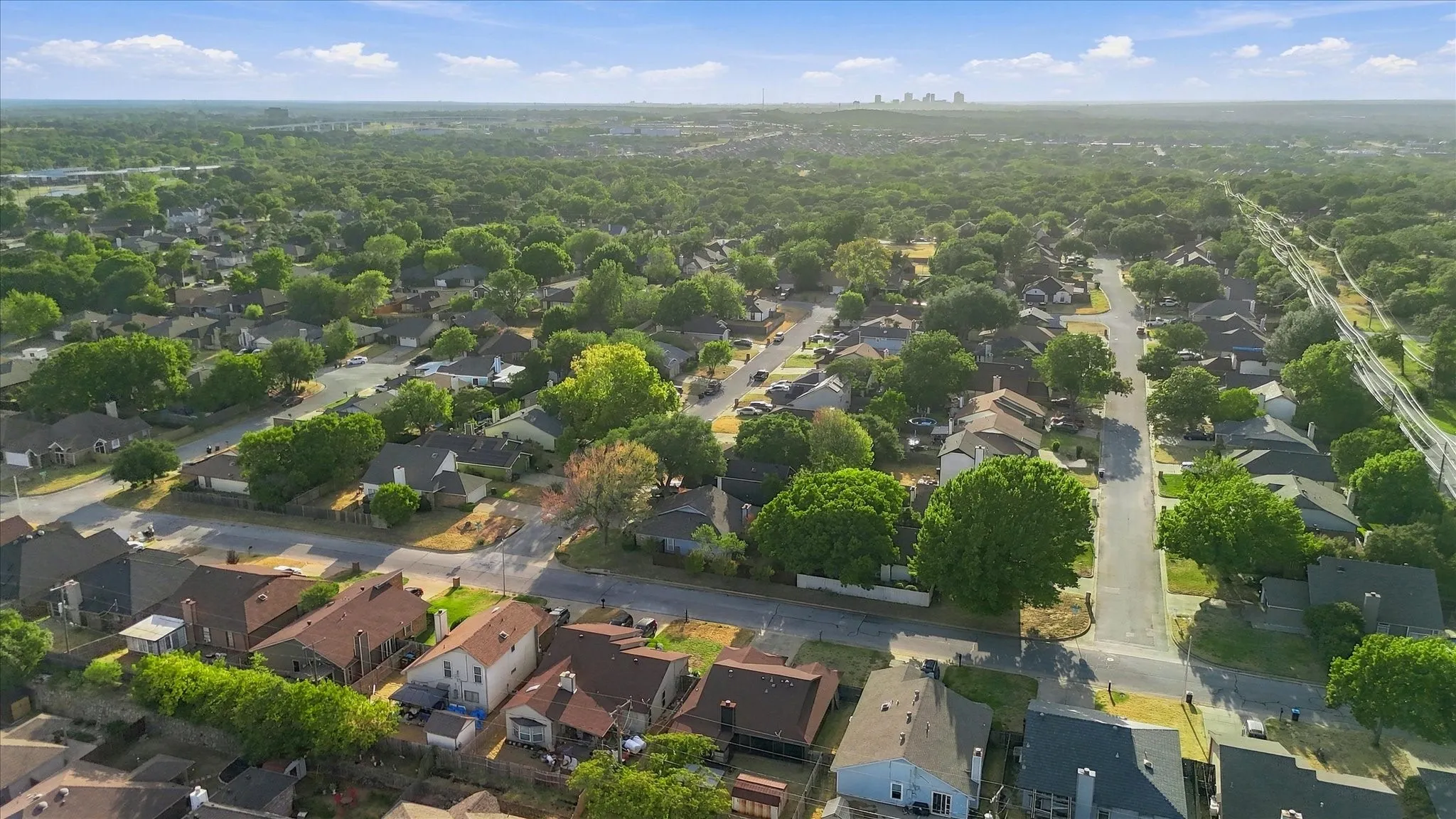 Aerial perspective showcasing a residential neighborhood with extensive tree coverage and a distant cityscape