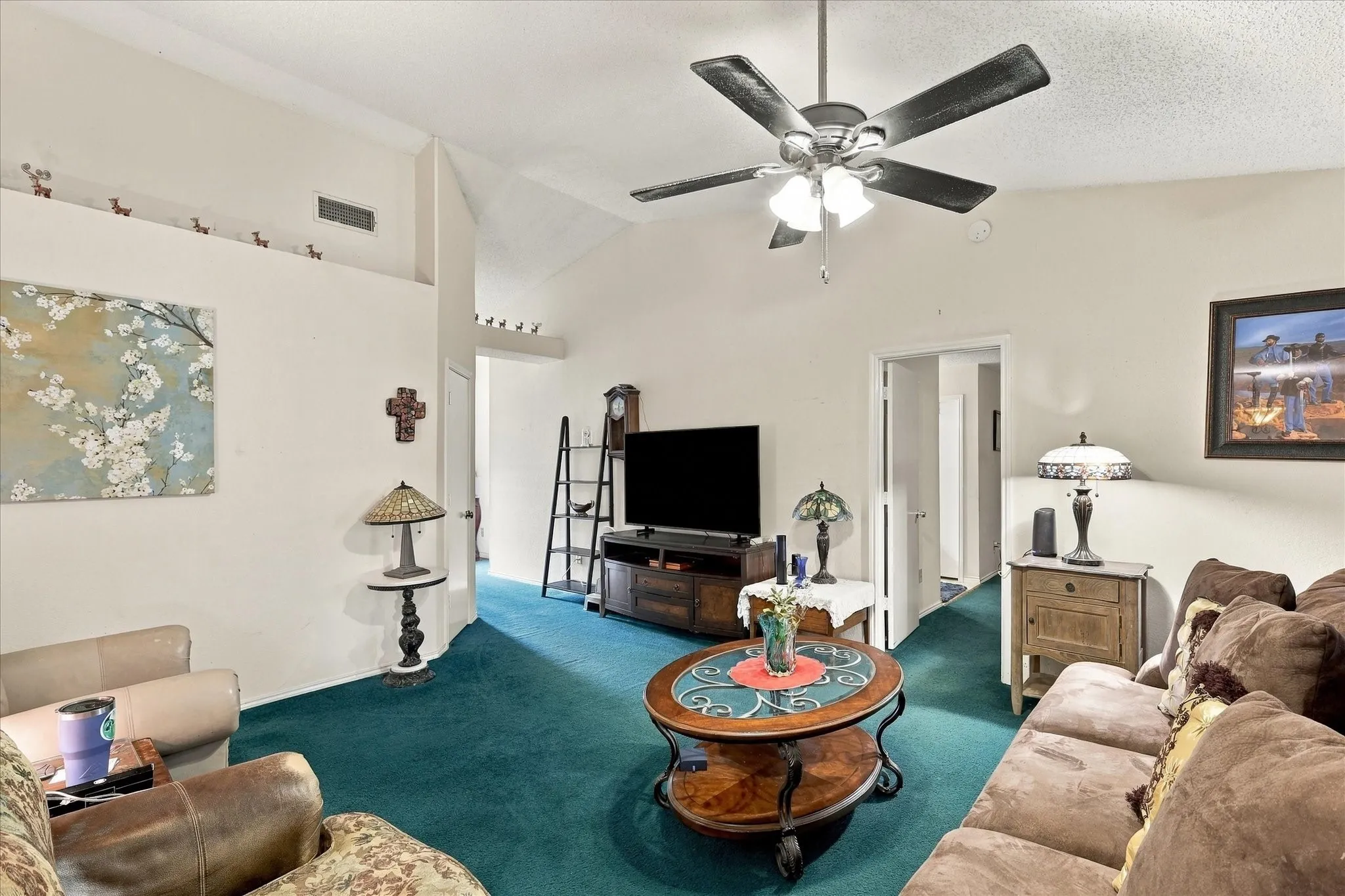 Vaulted ceiling with a ceiling fan, plush carpet flooring, and a decorative wall niche
