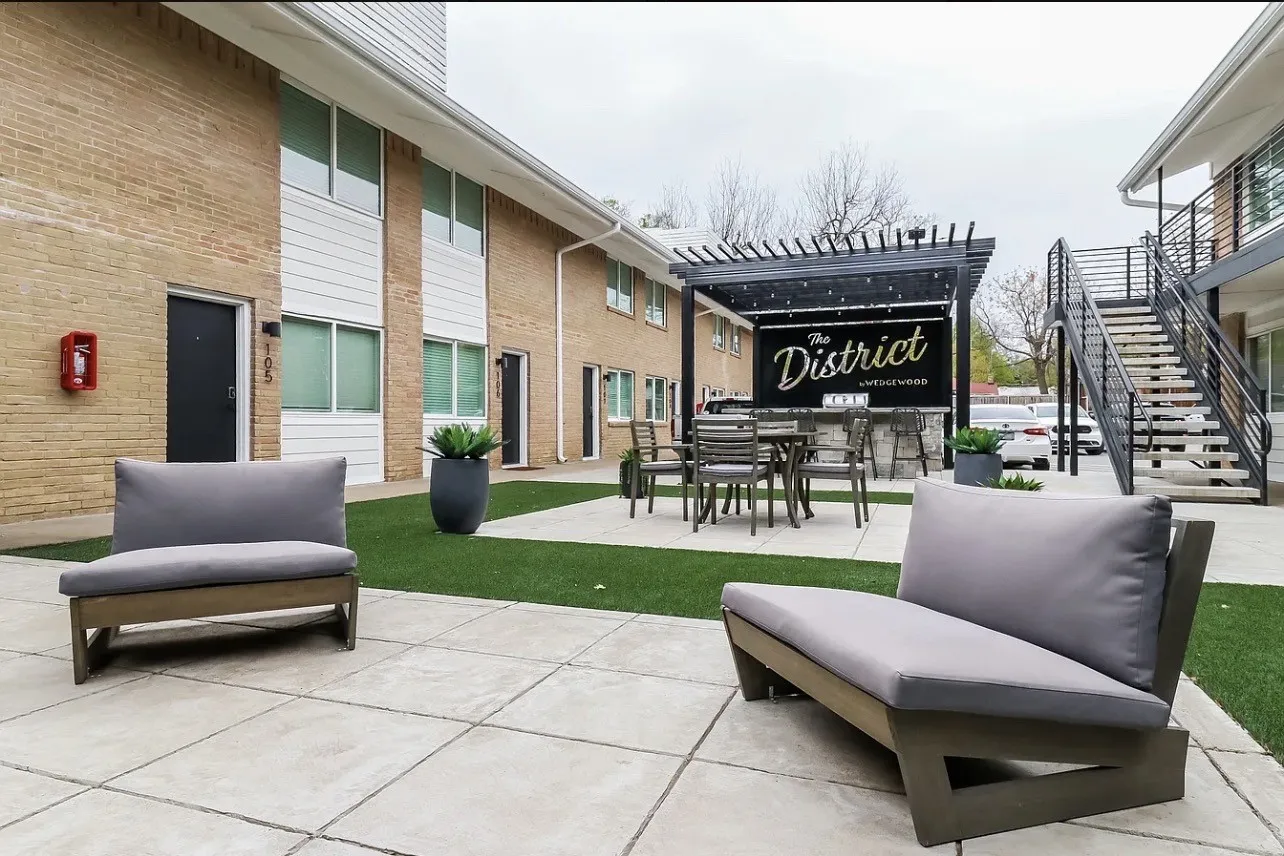 Spacious courtyard featuring concrete paver flooring, artificial turf, and a dark wood pergola