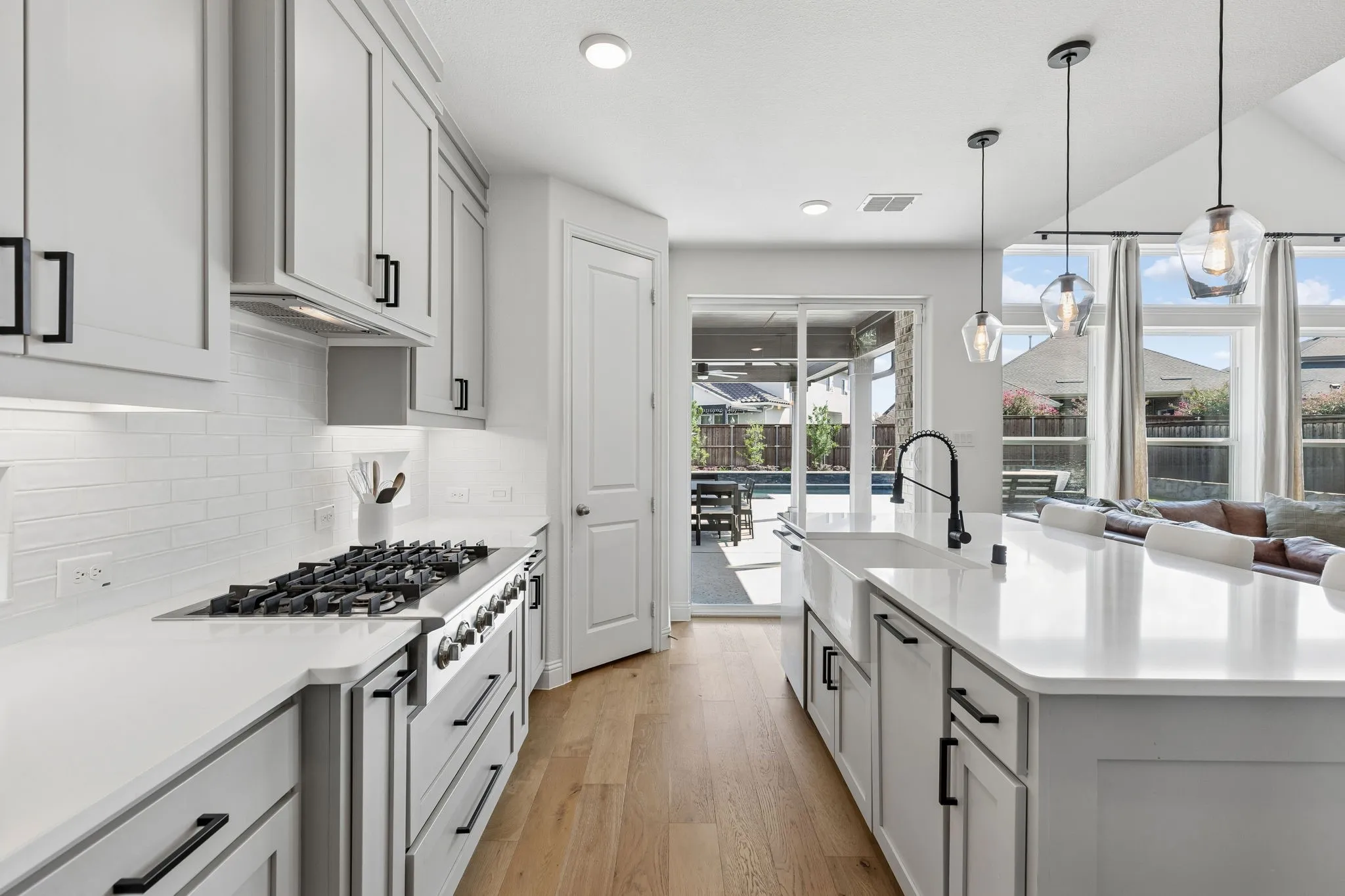 Another view of this chef's inspired kitchen! Notice the large gas cooktop, walk-in pantry, and the easy flow to the backyard paradise.