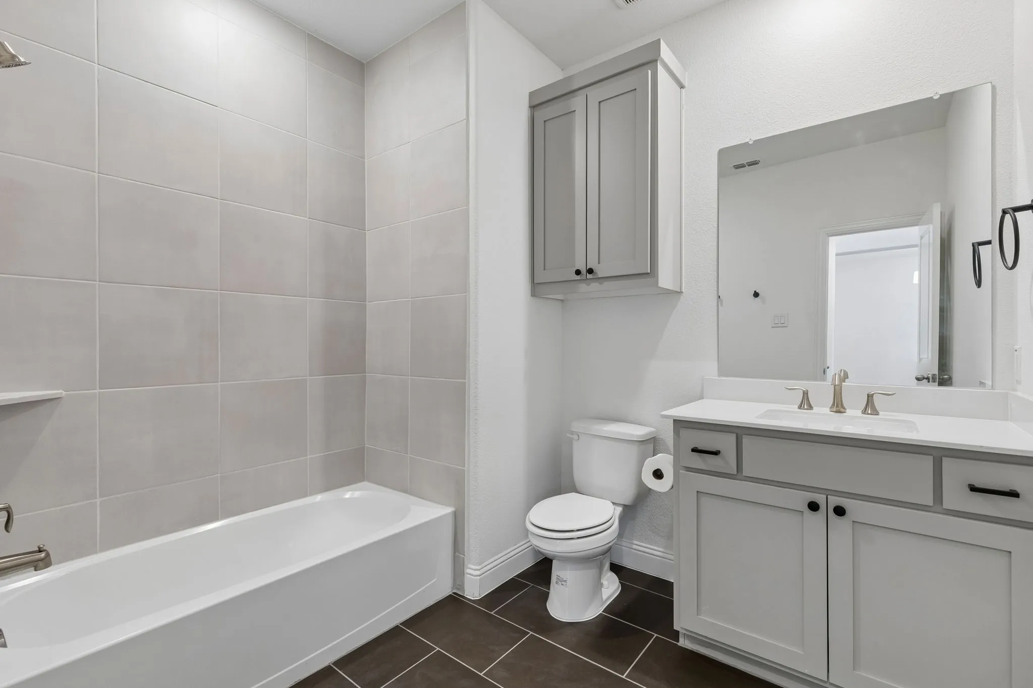 Fresh and inviting, this secondary first floor bath features a spacious vanity with abundant cabinetry, a tub and shower combination, crisp neutral finishes, and durable tile flooring. The timeless design offers both style and everyday functionality.