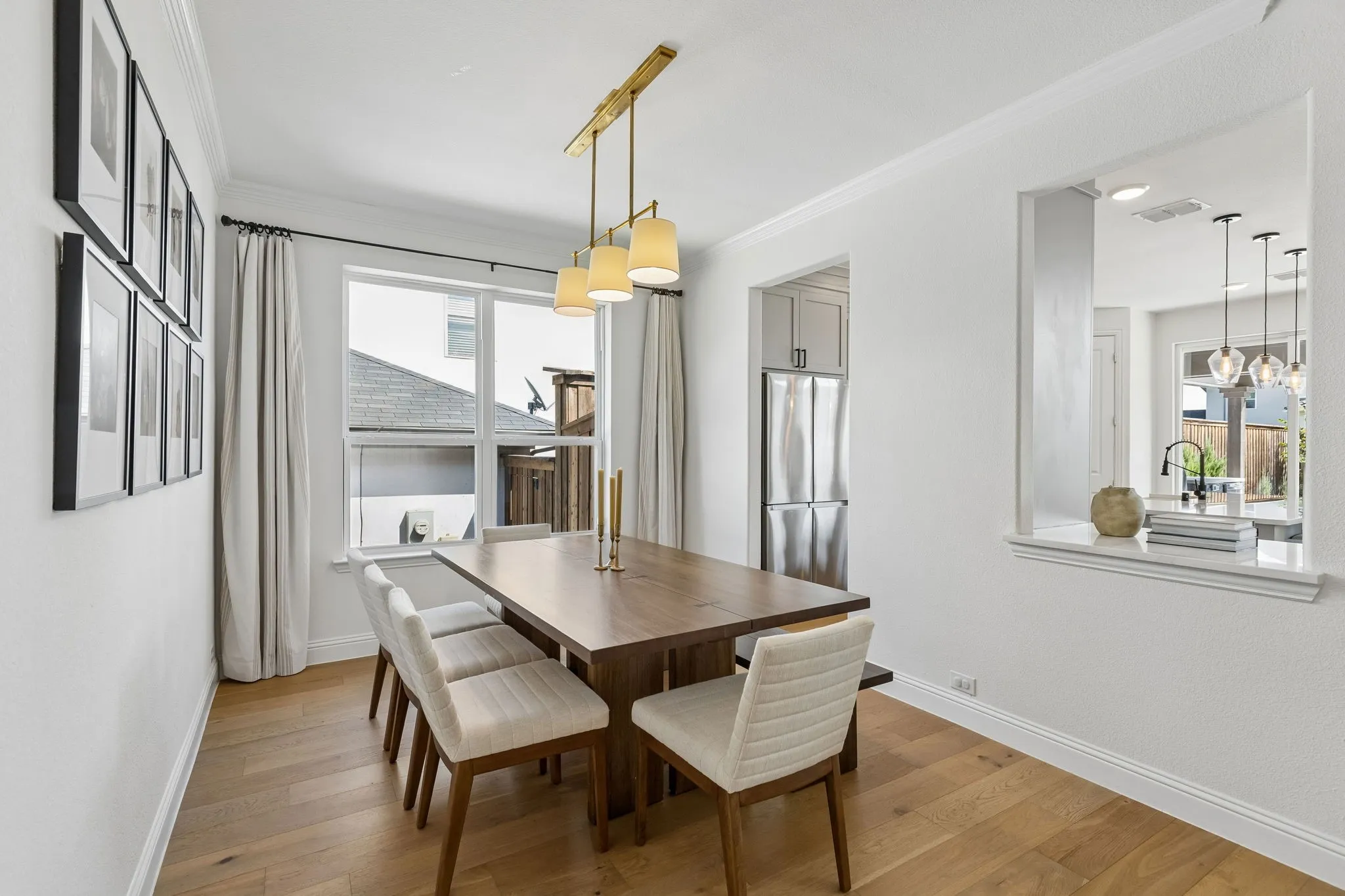 Elegant yet inviting, the dining room offers a gracious setting for everyday meals and memorable gatherings. Warm wood flooring, crown molding, an oversized dining table, and contemporary lighting create a refined space that flows naturally toward the adjoining kitchen and living areas.
