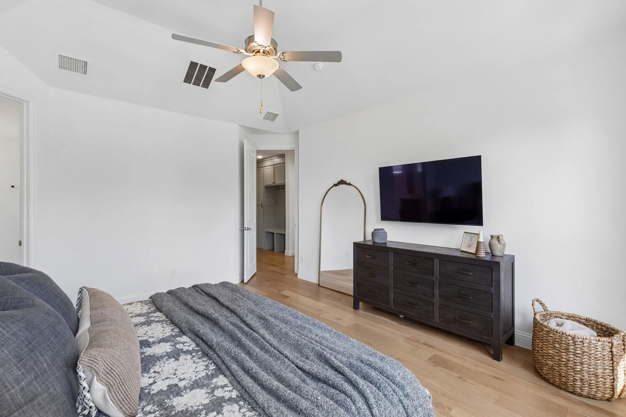The primary suite offers generous space for a king-sized retreat along with room for substantial furnishings and a comfortable sitting or reading area. Soft neutral tones, warm wood flooring, and abundant natural light create an atmosphere designed for relaxation.