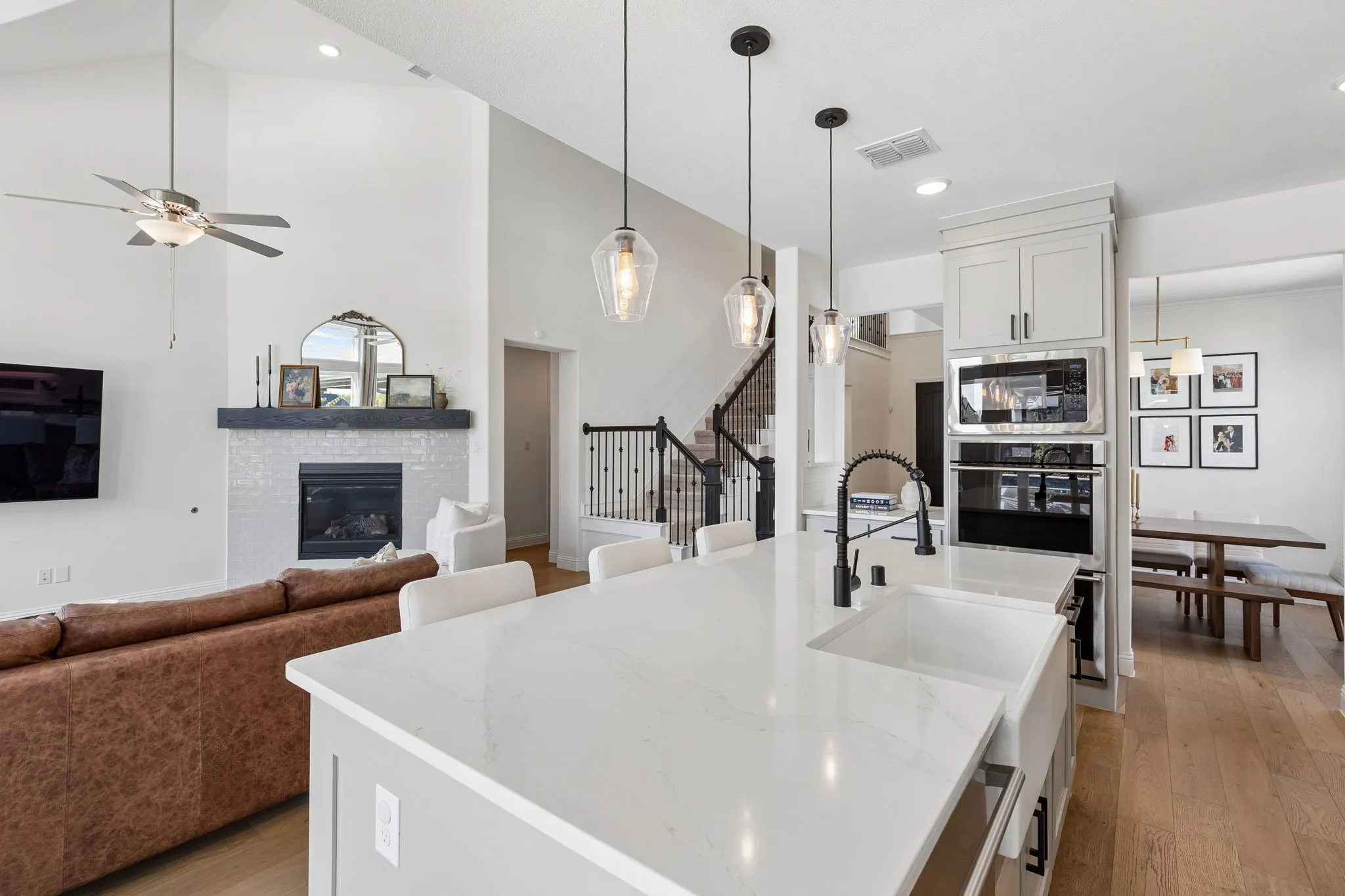 The heart of the home shines in this open-concept view, where the expansive quartz island overlooks the living room and fireplace, creating an inviting space designed for gathering, conversation, and entertaining.