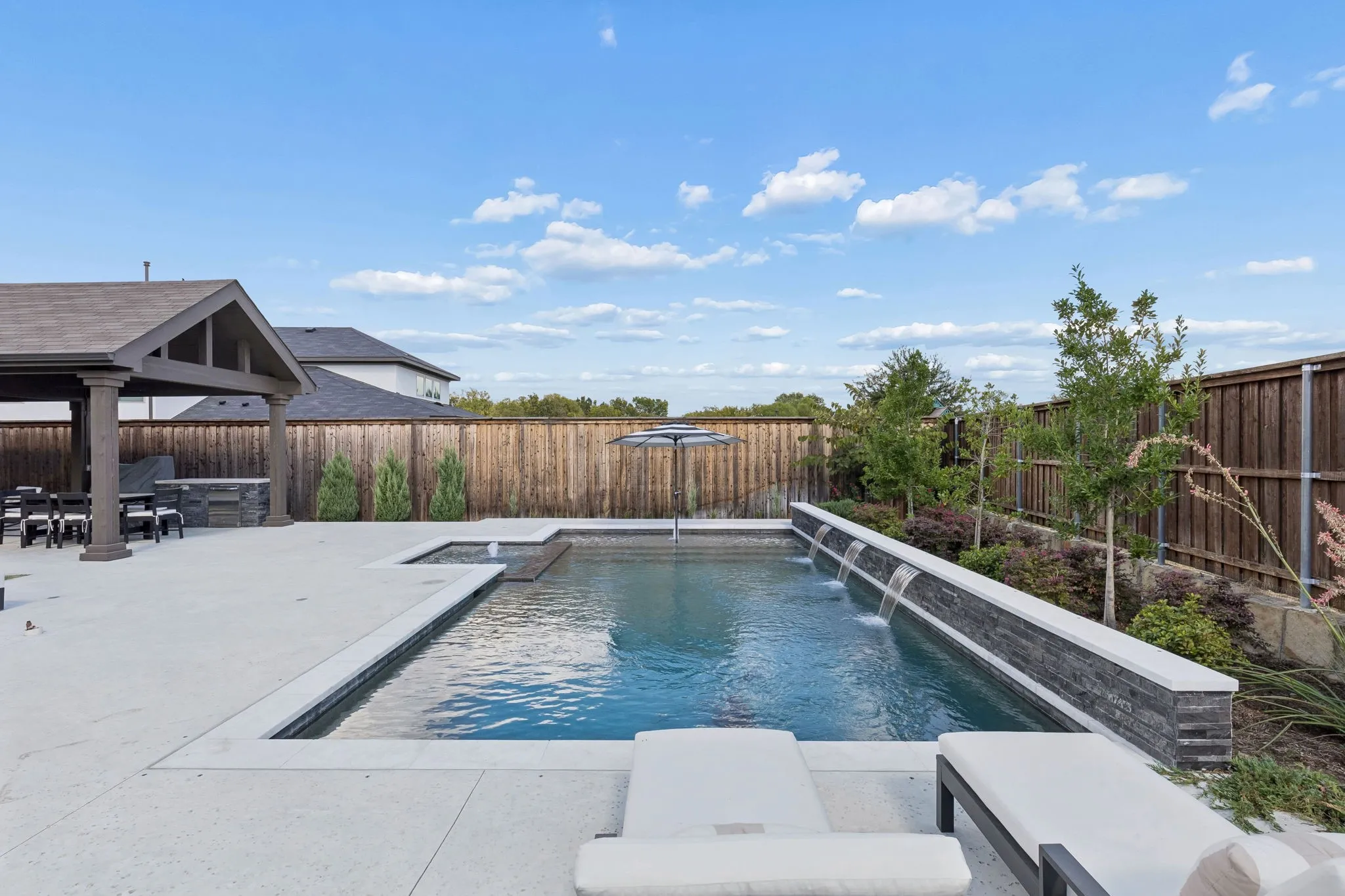 Resort-style outdoor living takes center stage with a sparkling pool accented by multiple cascading water features, an inviting spa, and thoughtfully landscaped surroundings. Comfortable lounge areas and an expansive patio create a picturesque setting for leisurely afternoons and memorable gatherings.