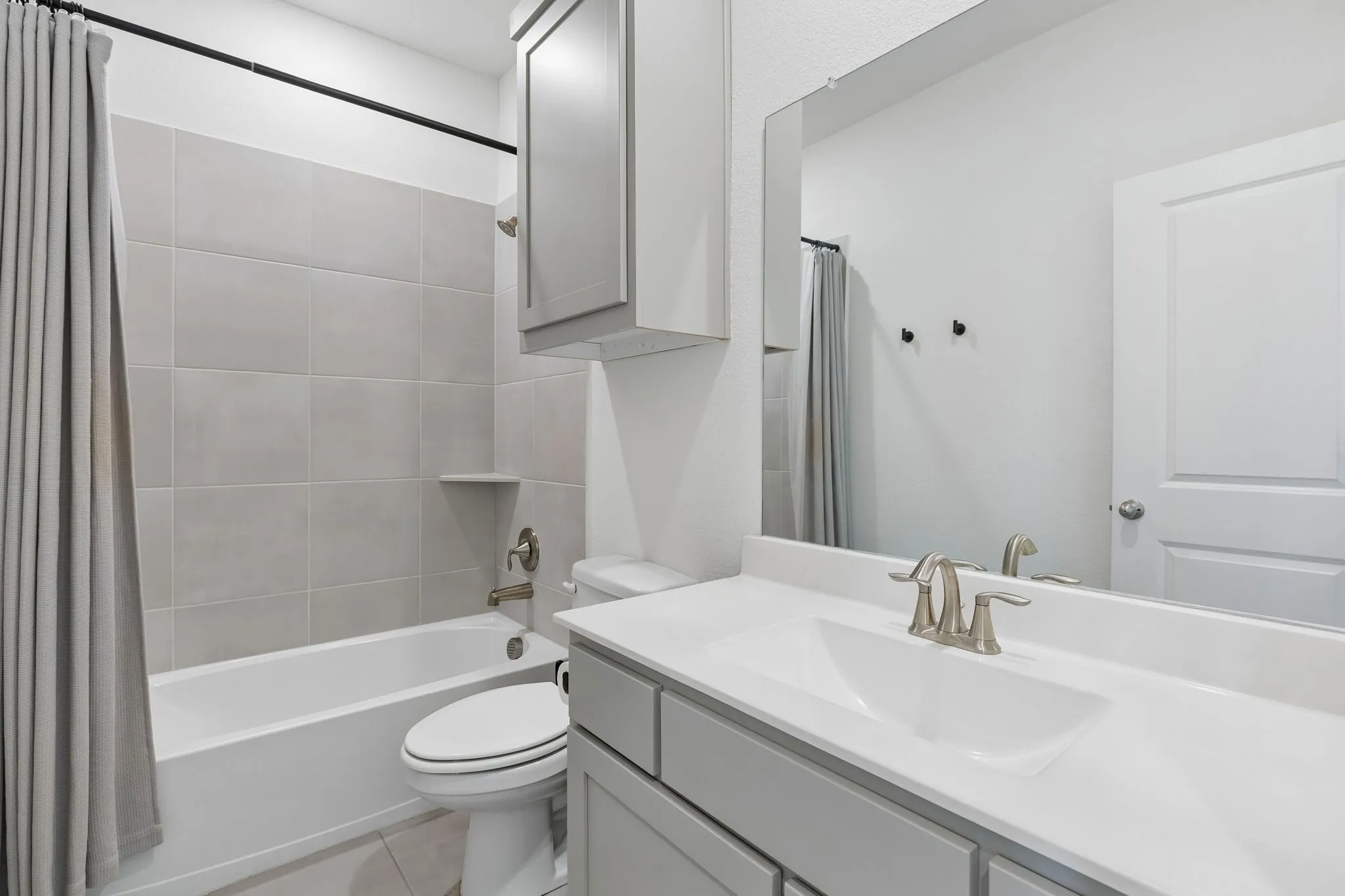 Second floor bright and thoughtfully appointed full bathroom features a spacious vanity, large mirror, brushed-metal fixtures, and a tub-shower combination accented by neutral tile.