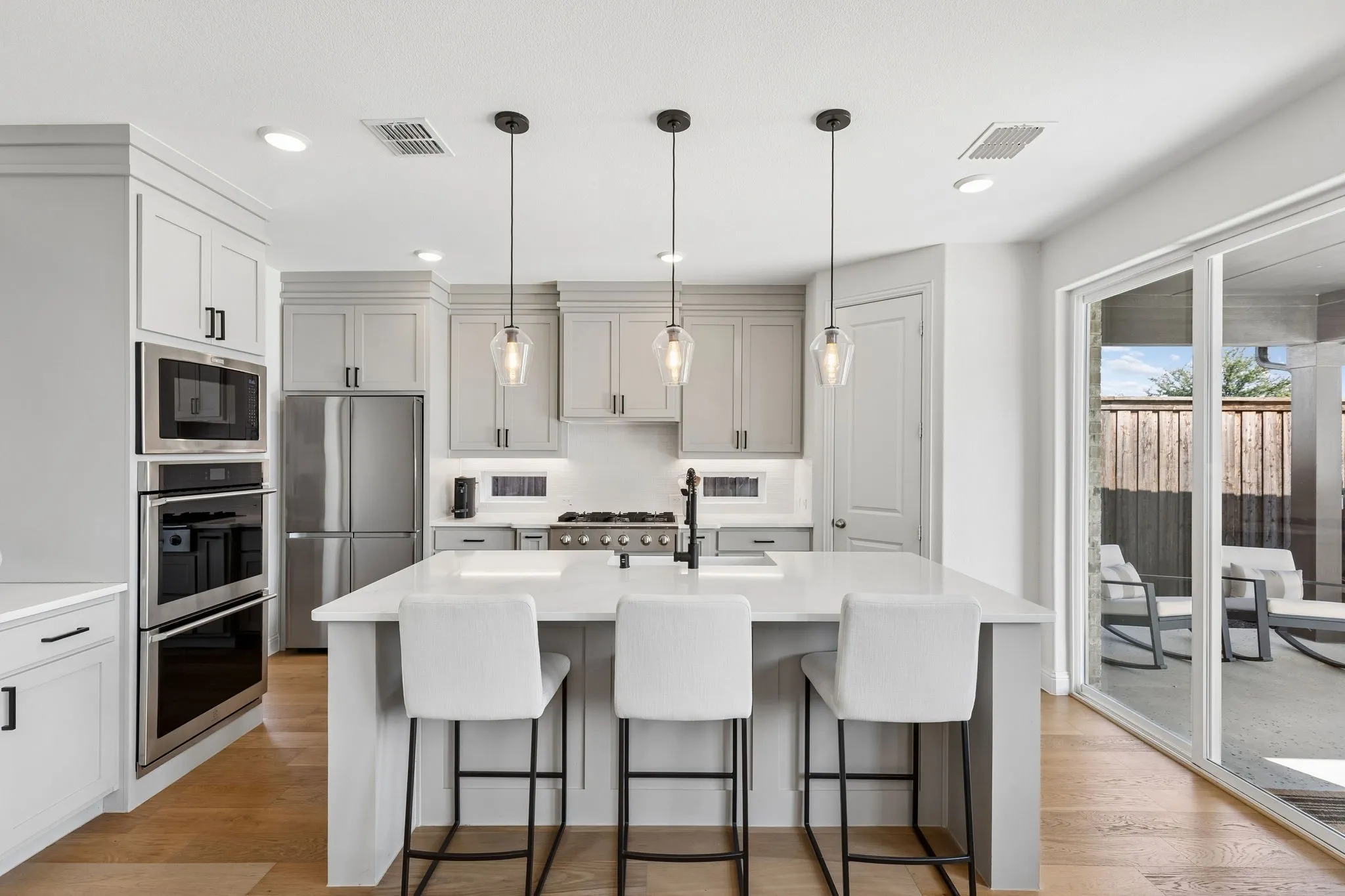 Beautifully updated kitchen centers around a large quartz island with available seating, crisp cabinetry, modern pendant lighting, stainless-steel appliances, gas cooktop, and abundant workspace—perfectly suited for everyday living and entertaining.