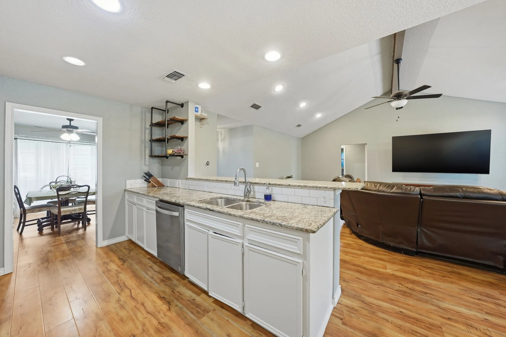 Kitchen featuring granite countertops, a white subway tile backsplash, white cabinetry, and stainless steel appliances