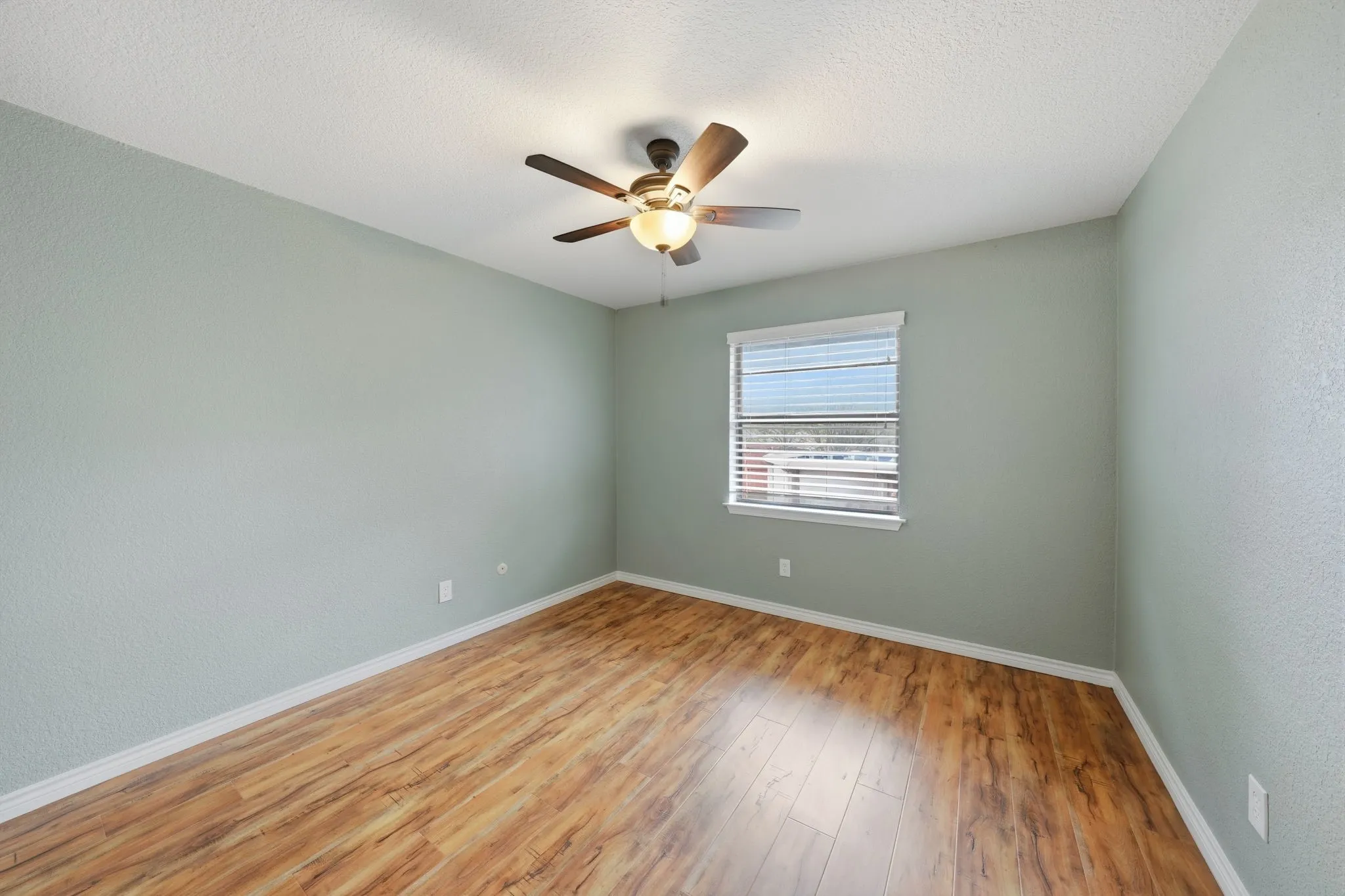 Secondary bedroom featuring wood-finish flooring, a window with blinds, and a ceiling fan with integrated lighting
