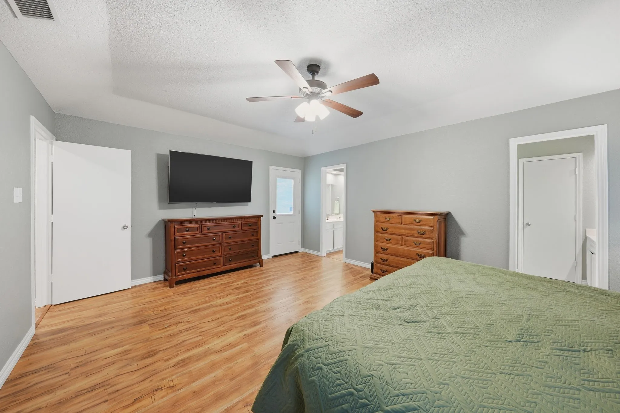 Primary with Tray ceiling, wood-finish flooring, ceiling fan with light fixture, light gray wall paint, white trim