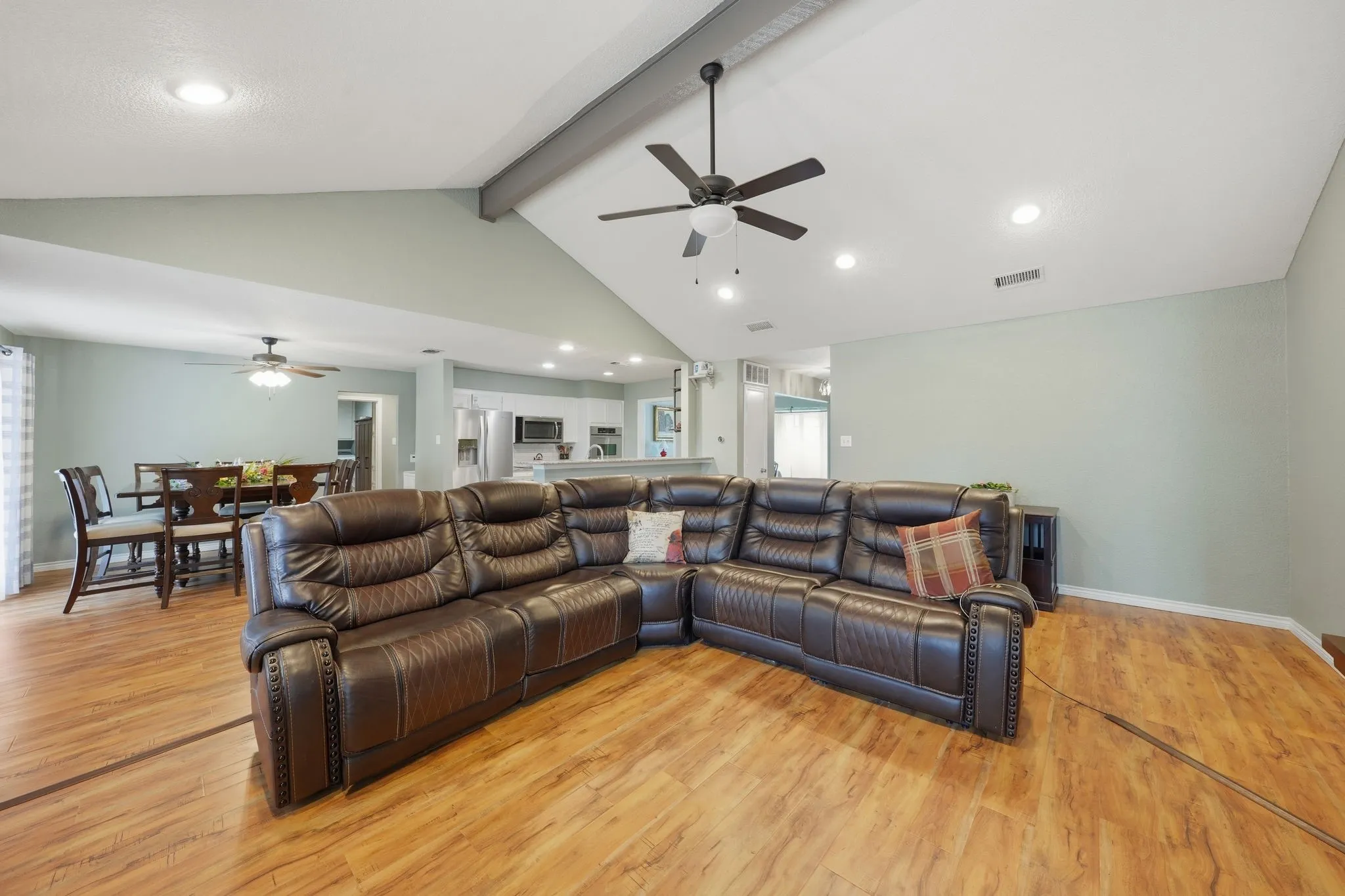 Vaulted ceiling with exposed beam, wood-finish flooring, recessed lighting, and ceiling fan