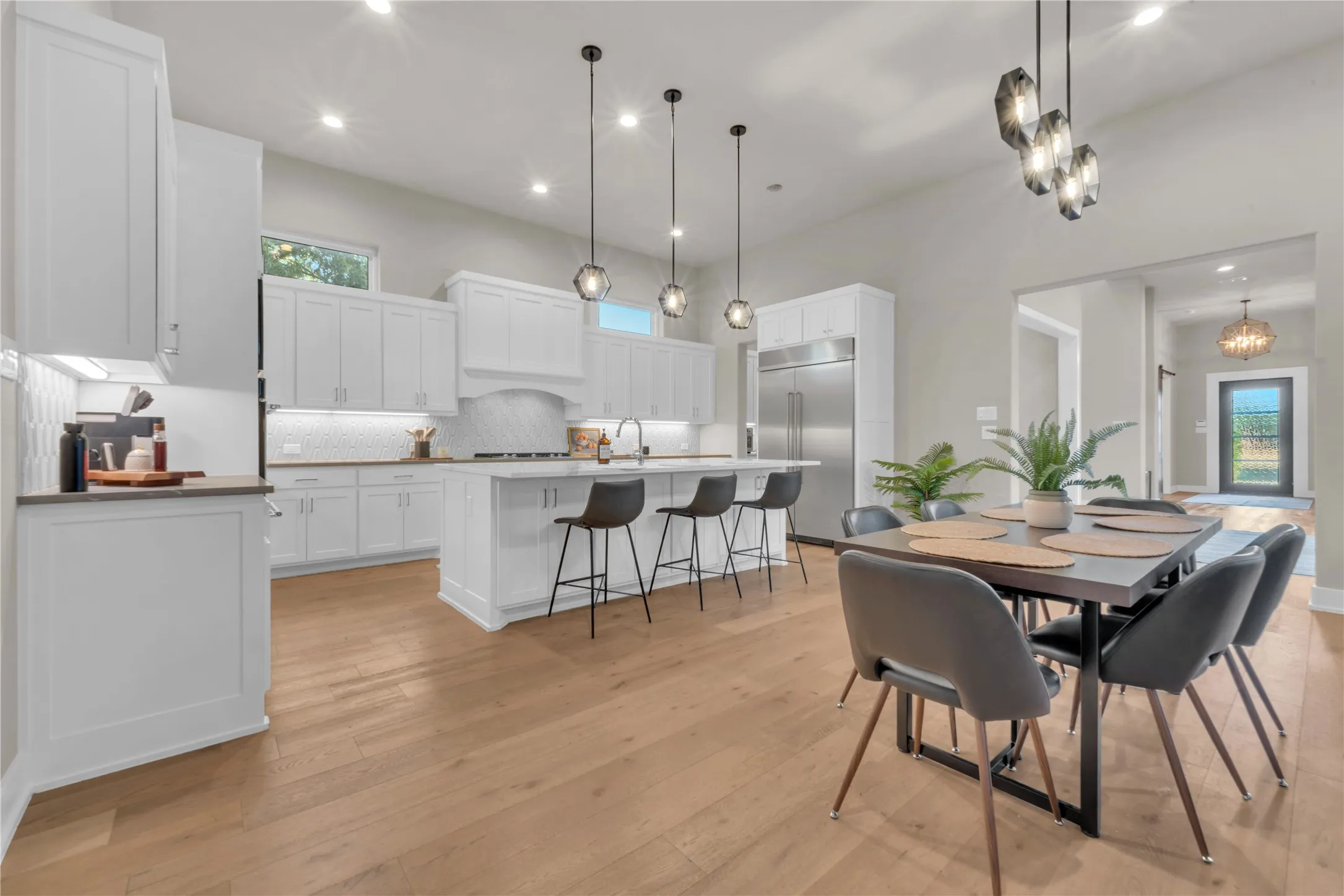 Open-concept living space with wood flooring, recessed lighting, and a soft closed cabinetry, a center Quartz island with seating, and stainless steel Kitchen-Aid appliances