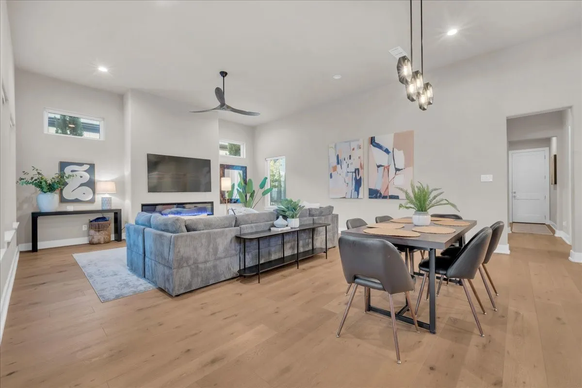 Open-concept living space featuring wood flooring, a contemporary ceiling fan, and a 74"linear fireplace