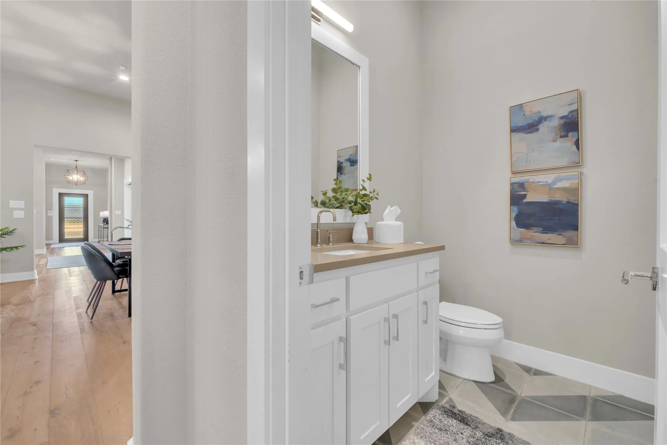 Powder room featuring a white vanity with brushed nickel fixtures, a neutral countertop, and patterned floor tiling