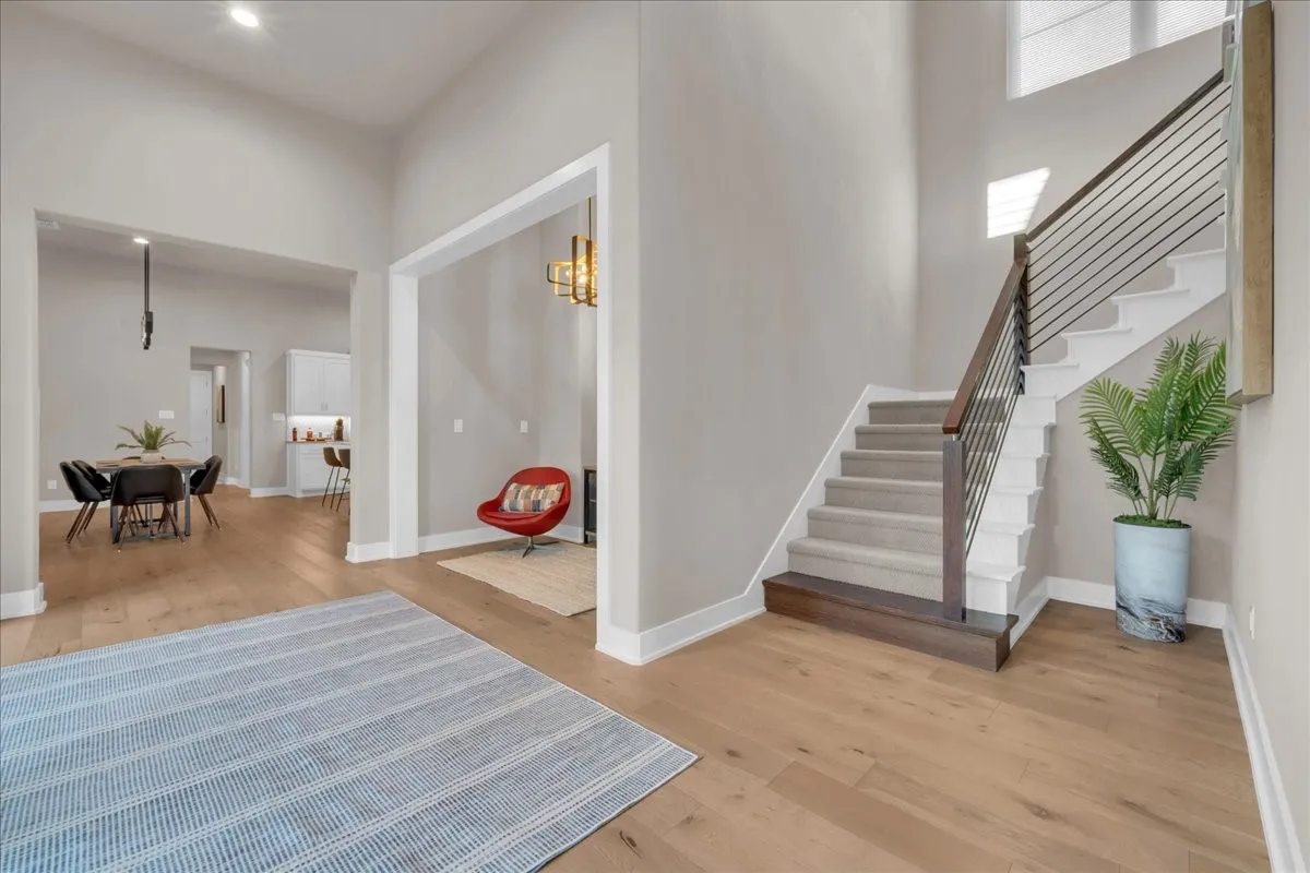 7.5 Wood flooring throughout, modern staircase with metal balusters, and a recessed lighting feature in the 12' high ceiling