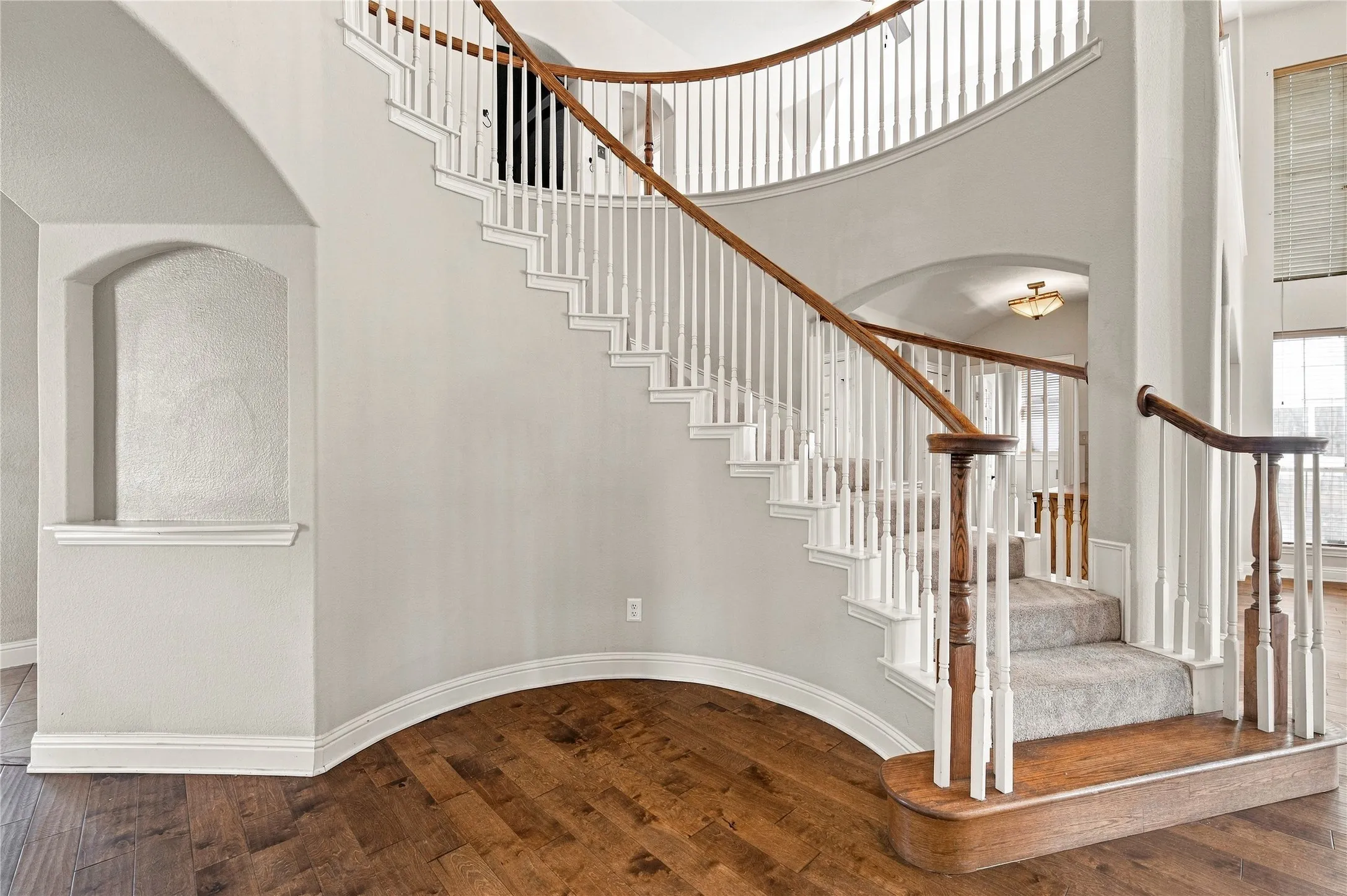 Curved staircase with wood-finish handrails and white balusters