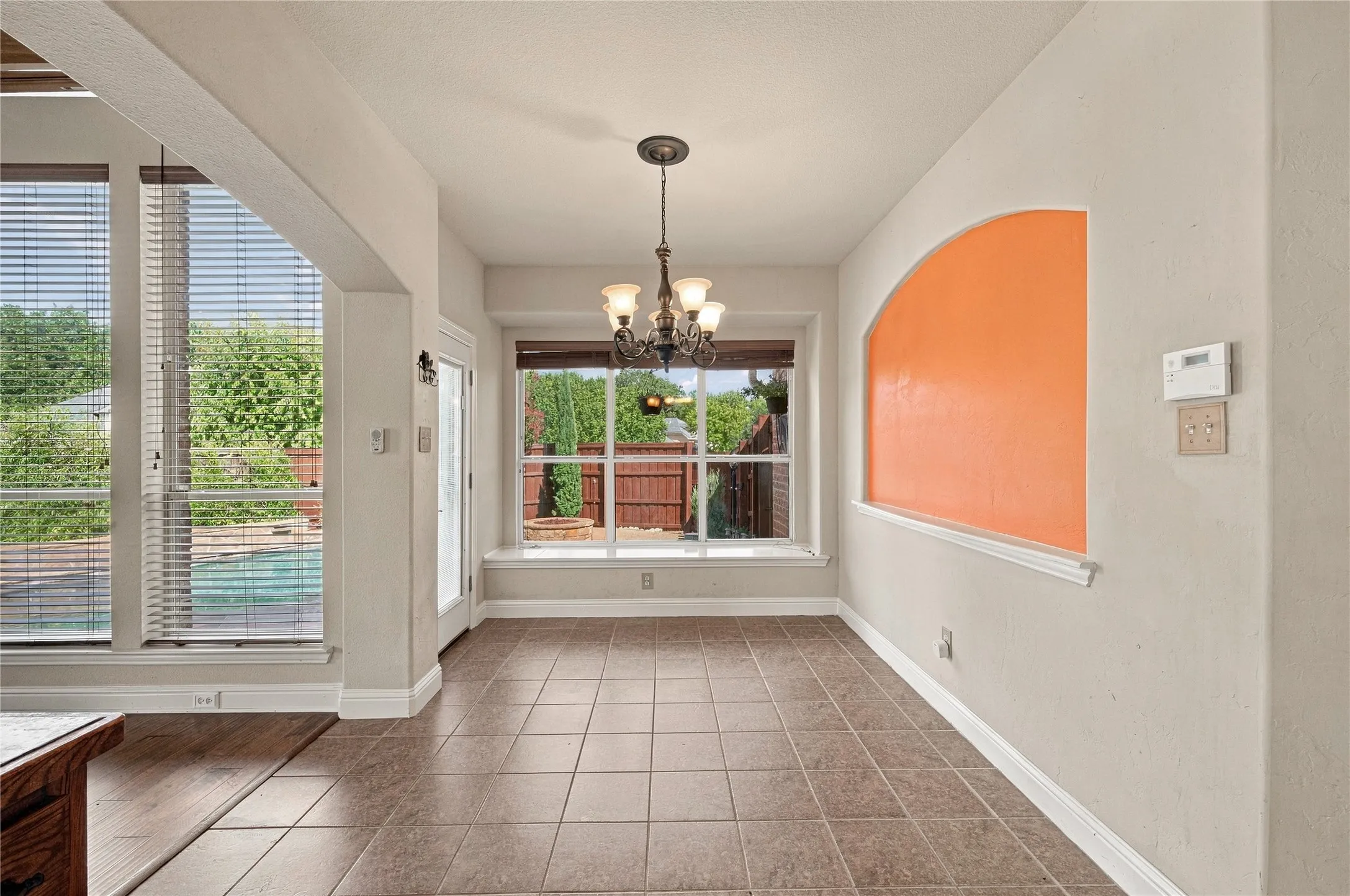 Tile flooring, large windows, window bench, decorative wall niche, and a chandelier