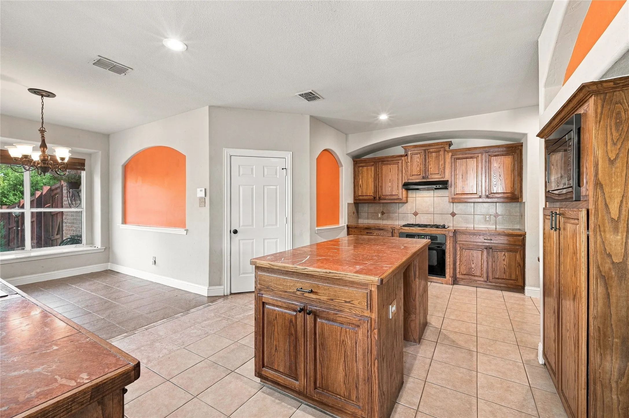 Kitchen featuring wood cabinetry, a center island with a stone-finish countertop, tile flooring, and recessed lighting