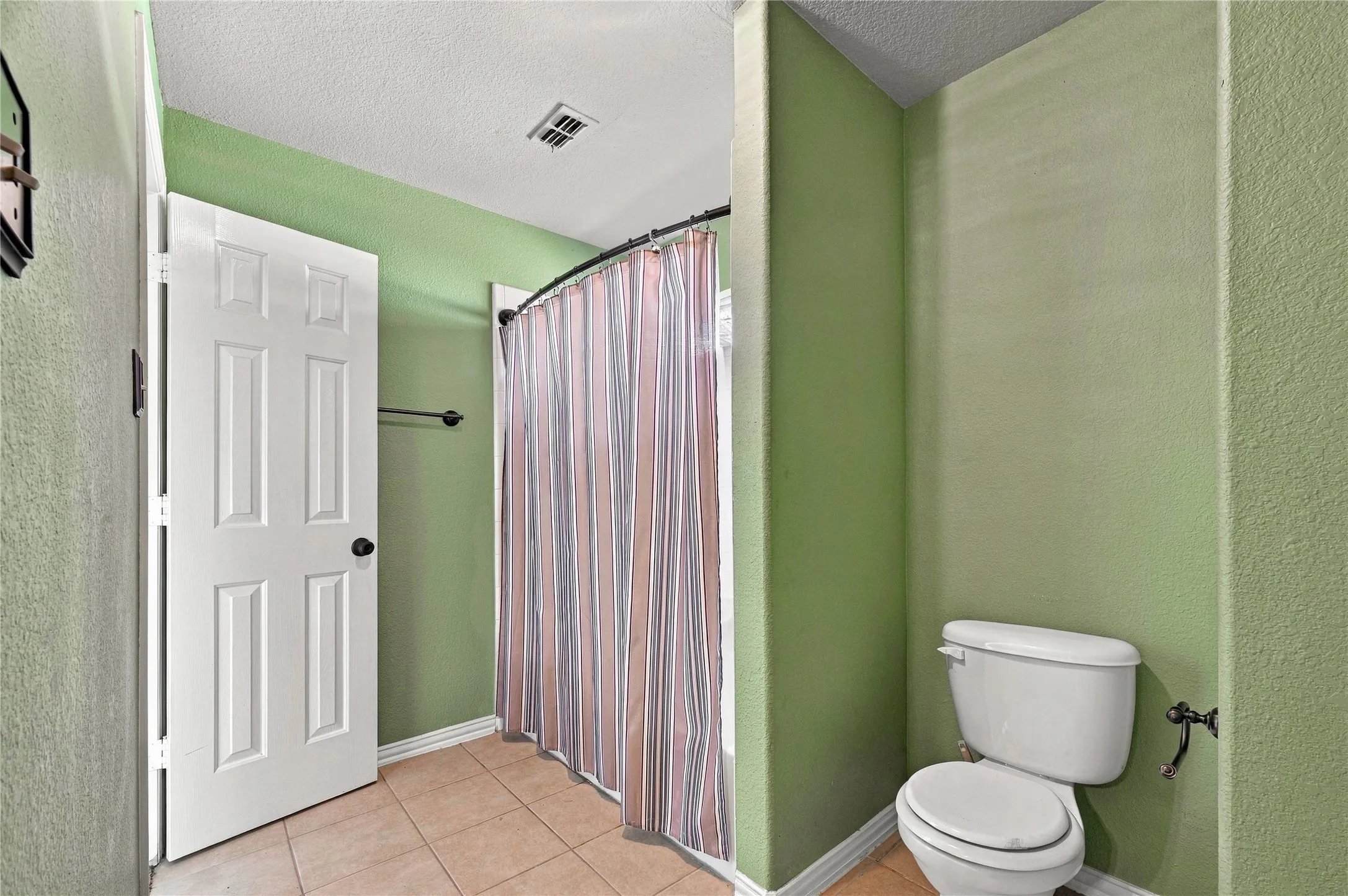 White paneled door, ceramic tile flooring, and a shower area with a curved rod