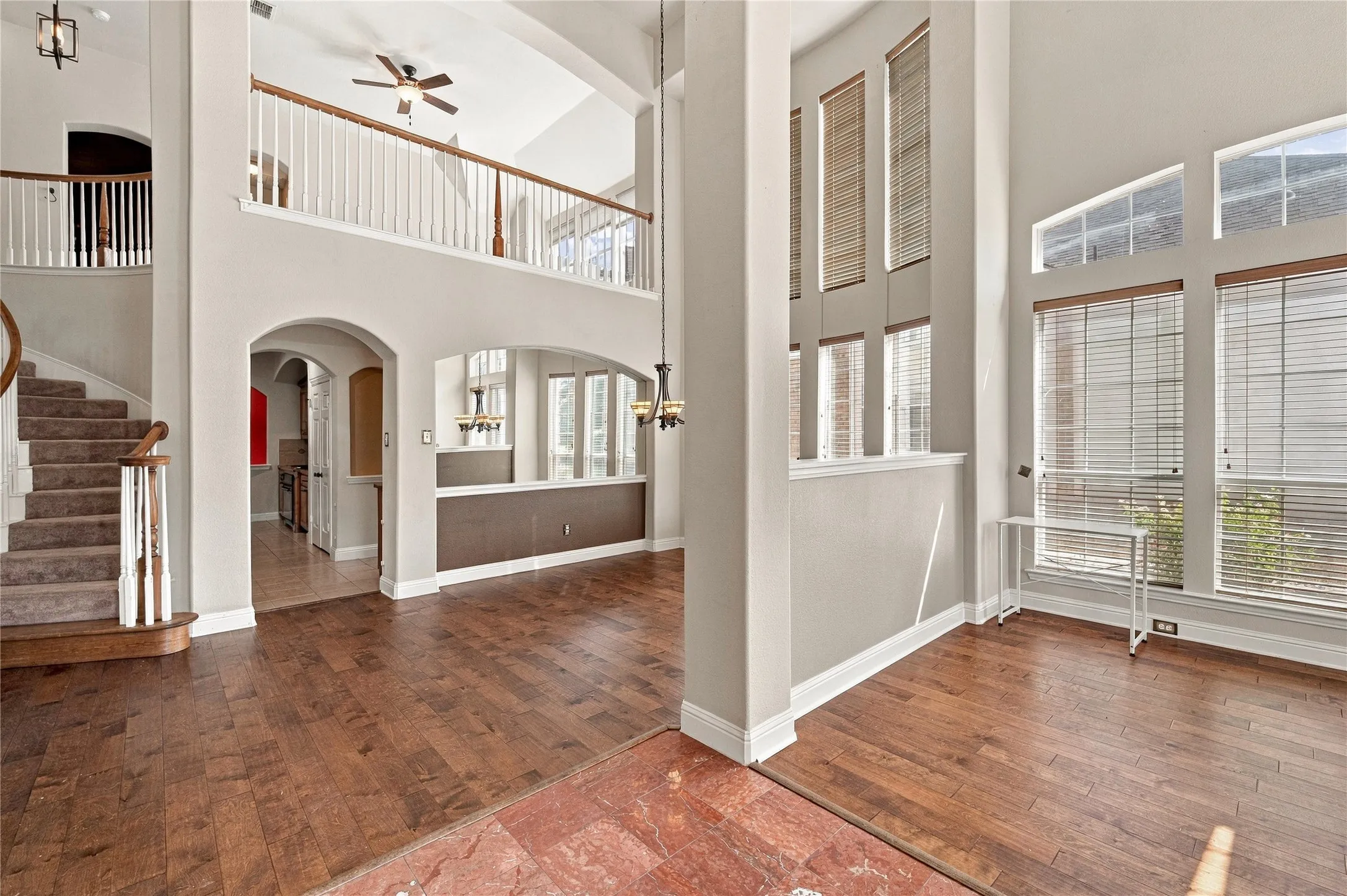 Two-story living area with wood-finish flooring, vaulted ceilings, and a second-story balcony with white balusters