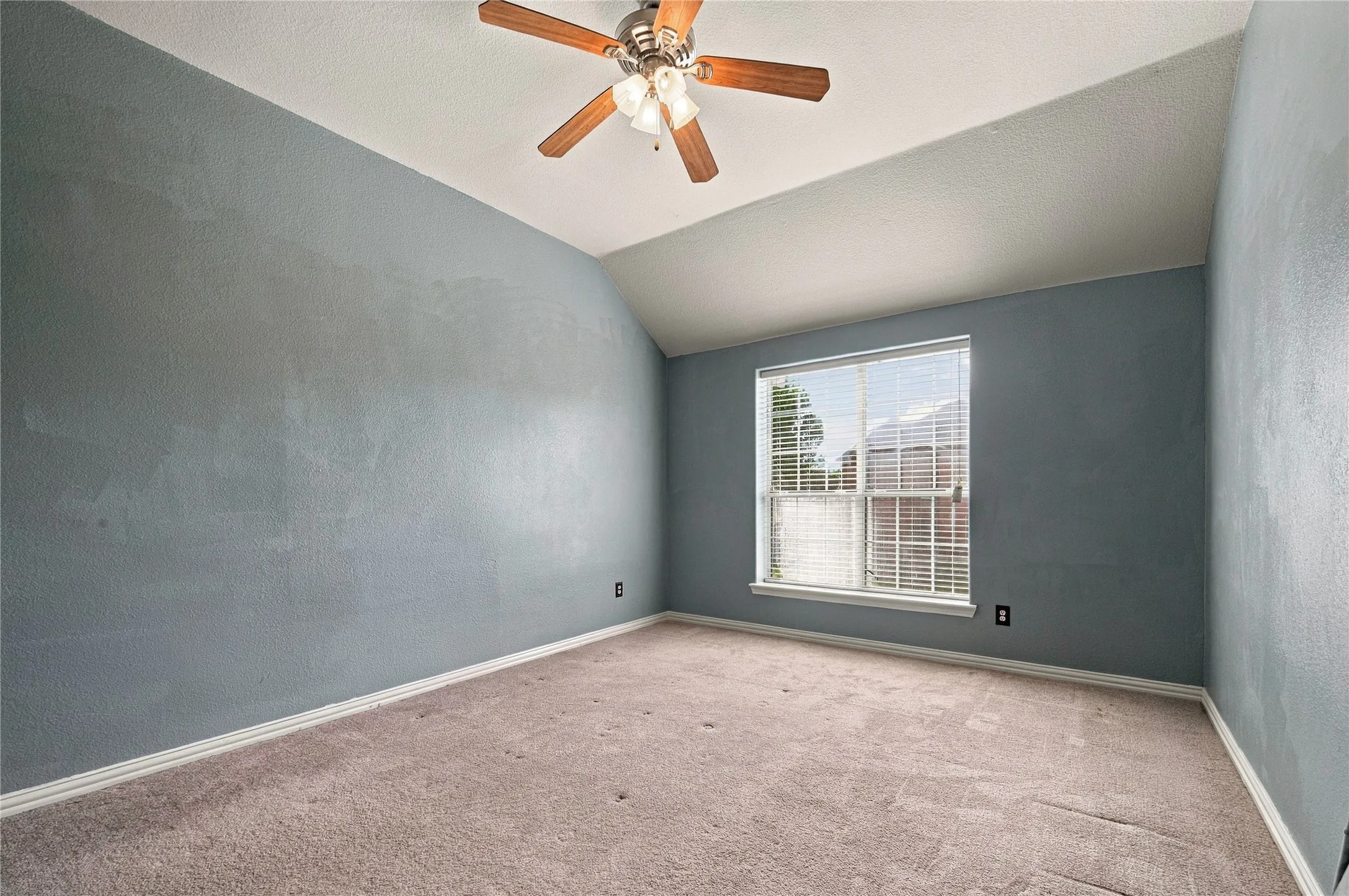 Carpeted room featuring a sloped ceiling and a window with blinds