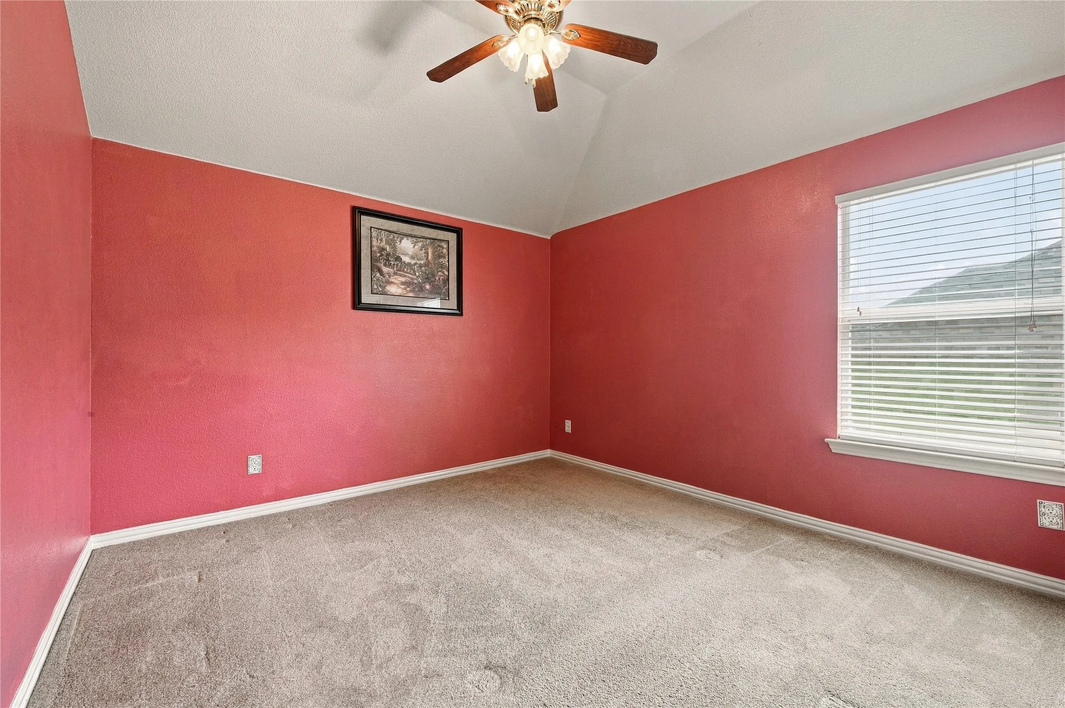 Vaulted ceiling with a ceiling fan, carpeted flooring, and a window with blinds