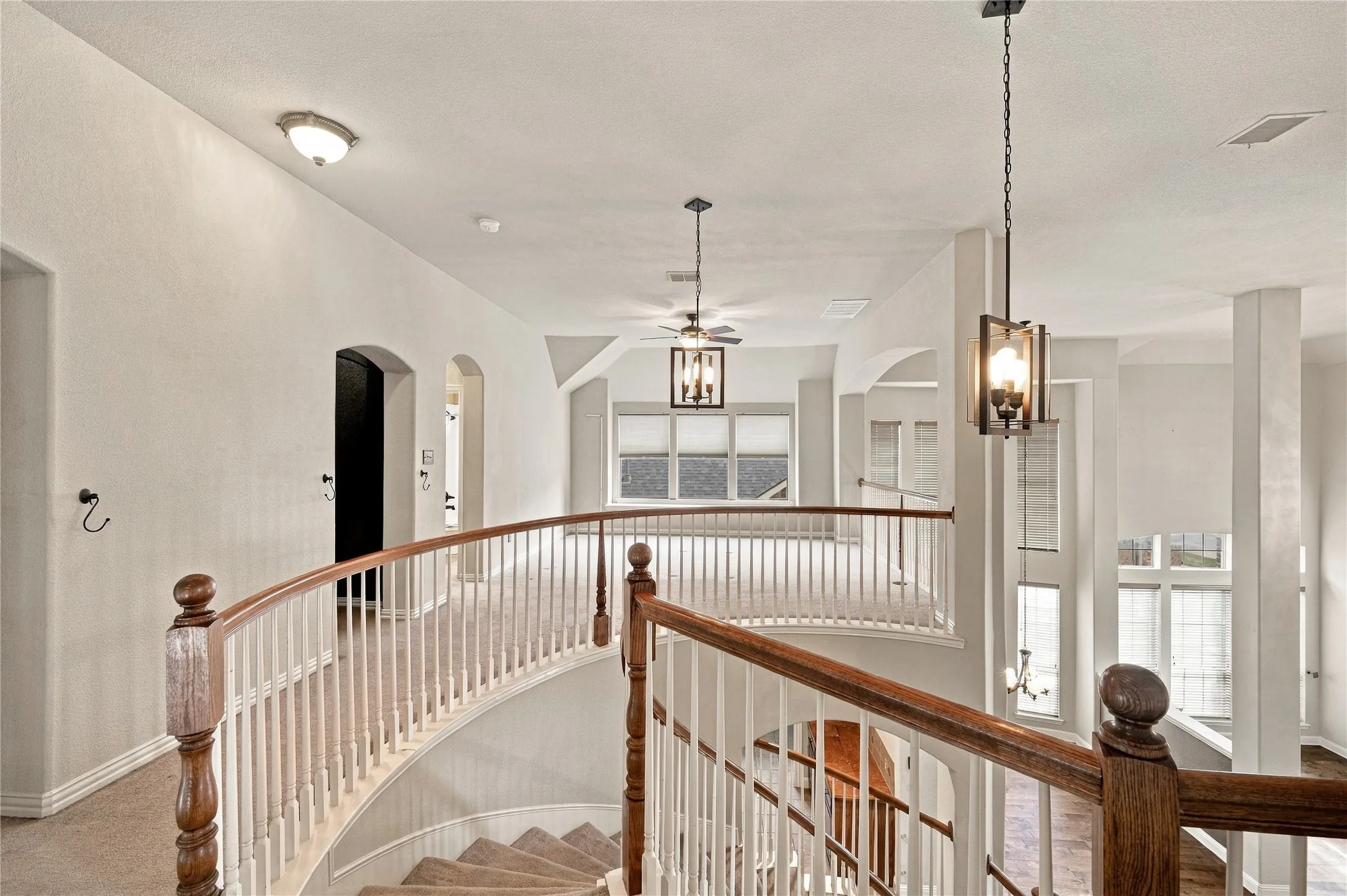 Curved staircase with wood handrail, white balusters, and carpeted treads
