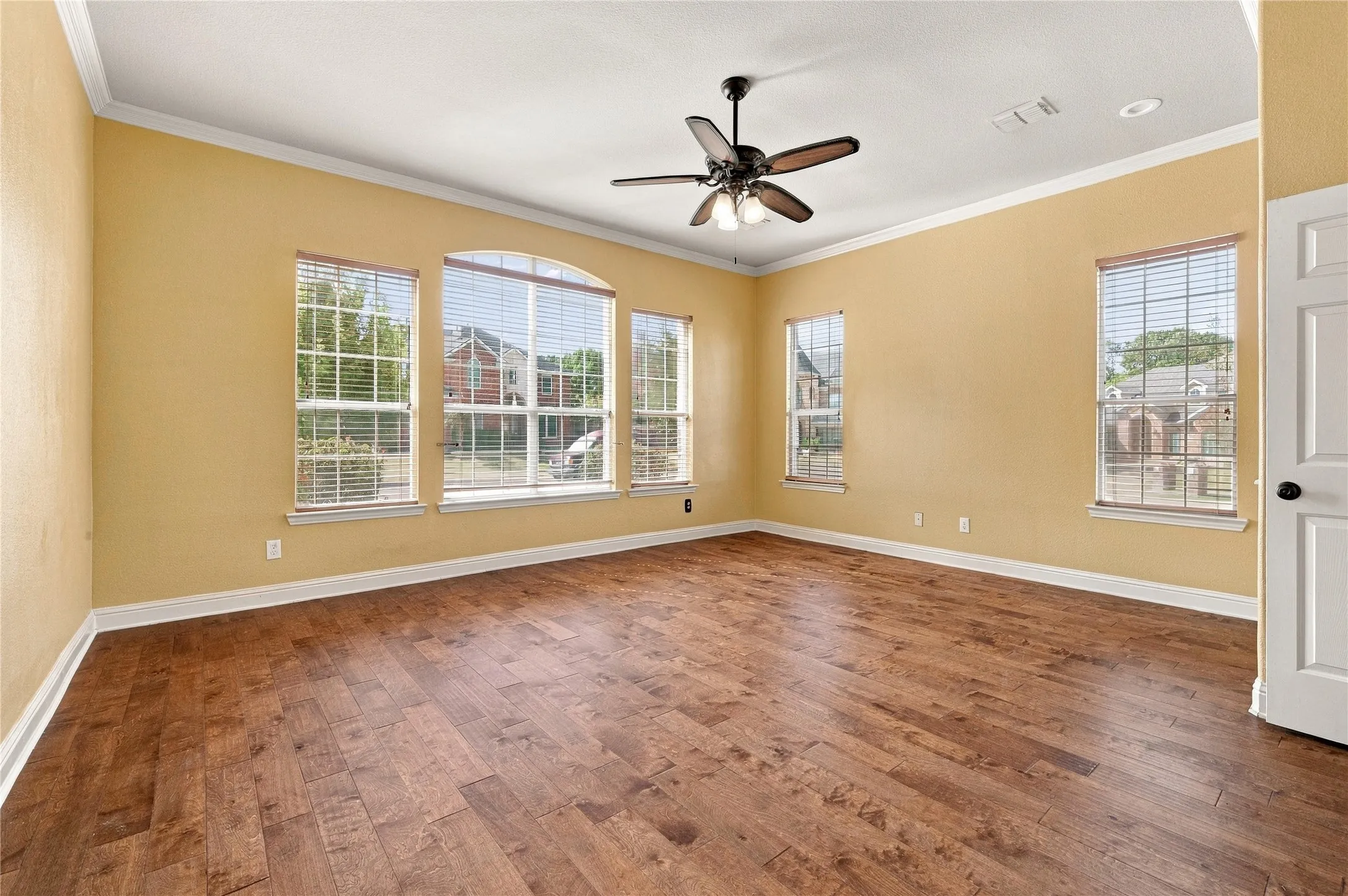 Wood-finish flooring, multiple windows, ceiling fan with integrated lighting, recessed lighting, and crown molding