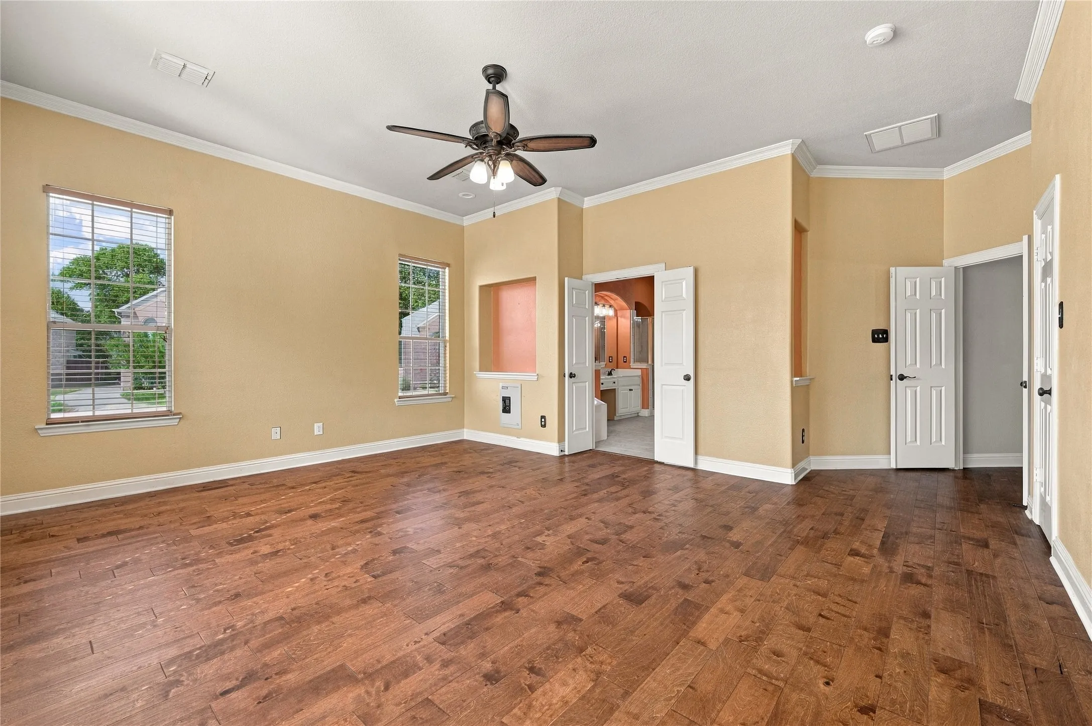 Spacious room featuring wood-finish flooring, crown molding, and a ceiling fan