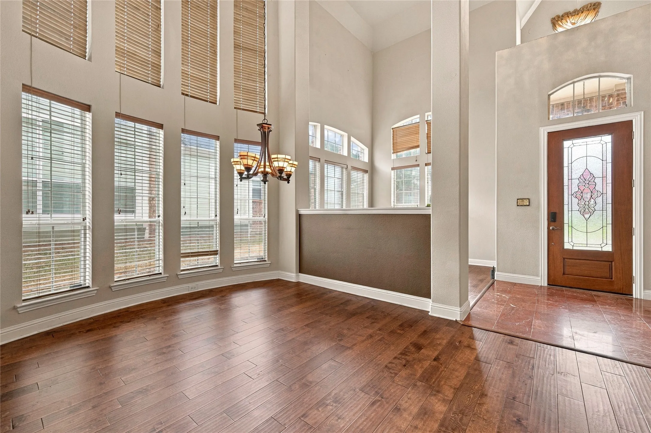 Double-height ceilings, a decorative chandelier, and wood-finish flooring