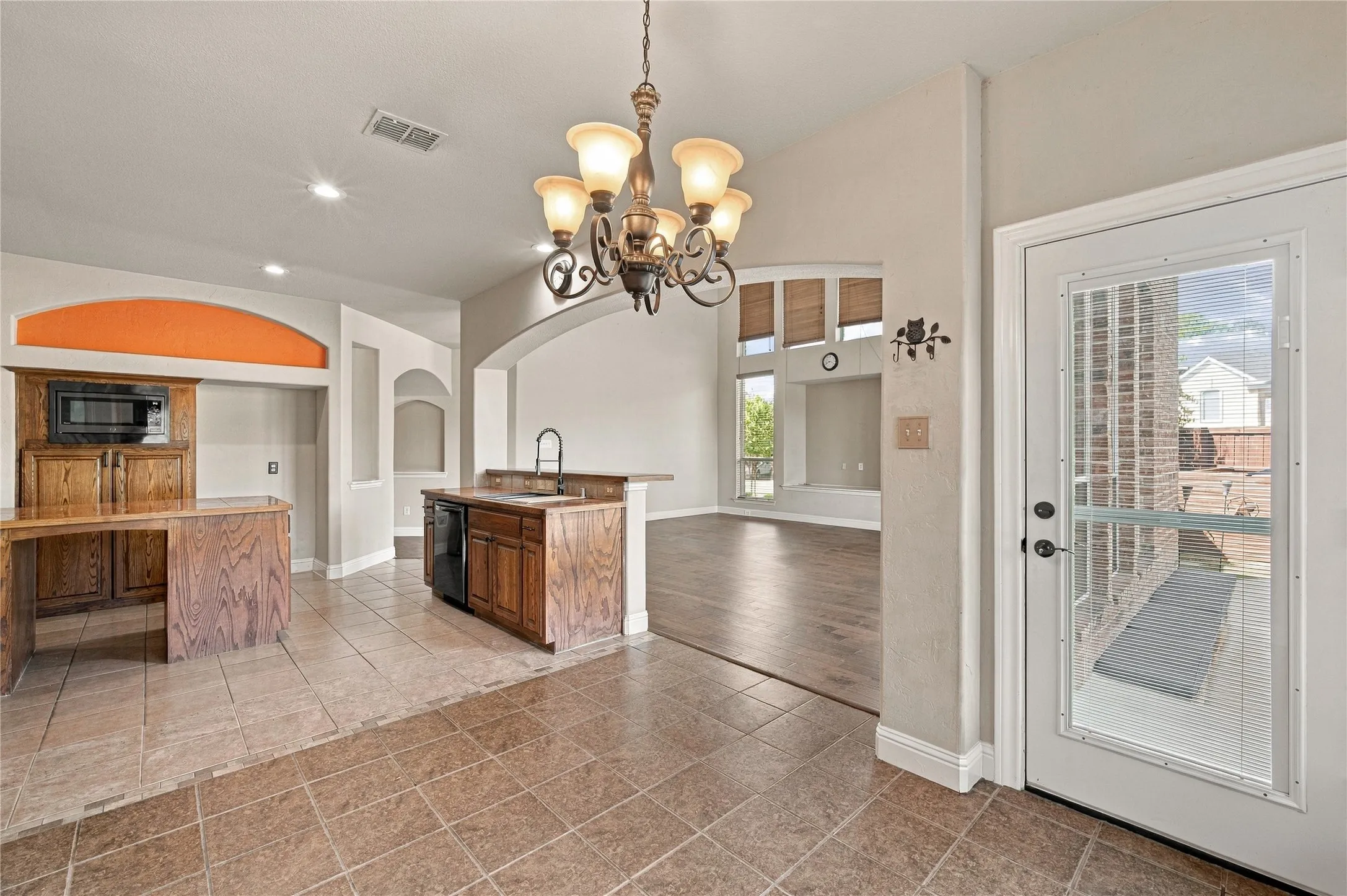 Tiled flooring, wood-finish cabinetry, built-in microwave, integrated dishwasher, and a glass-paneled door