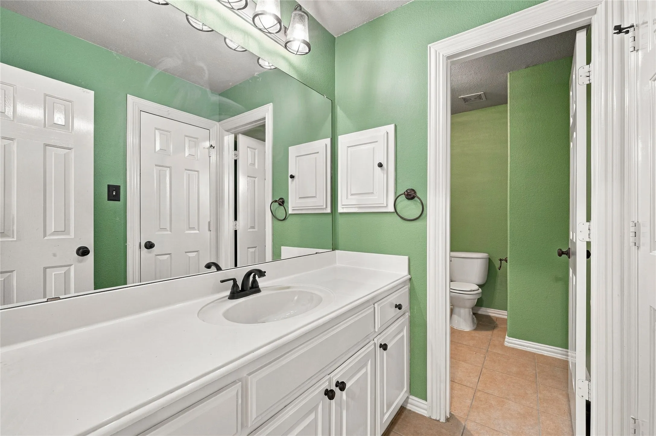 White vanity with integrated sink, black faucet, and full-width mirror