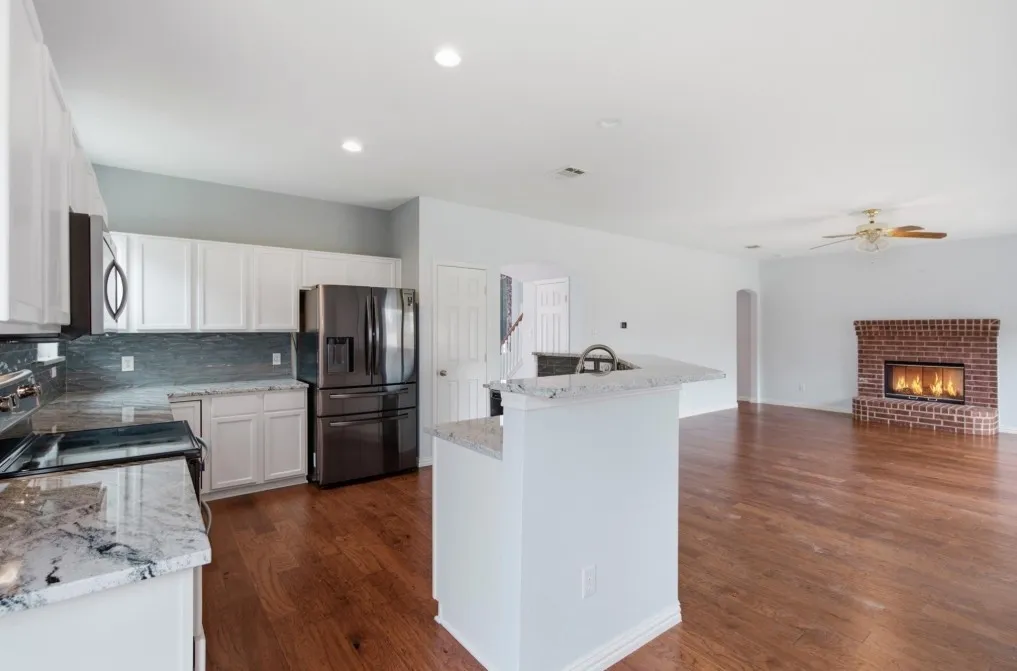 Kitchen with white cabinetry, granite countertops, stainless steel appliances, and a tile backsplash