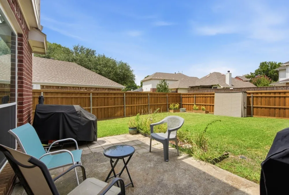 Expansive backyard with a concrete patio, wood fencing, and a storage shed